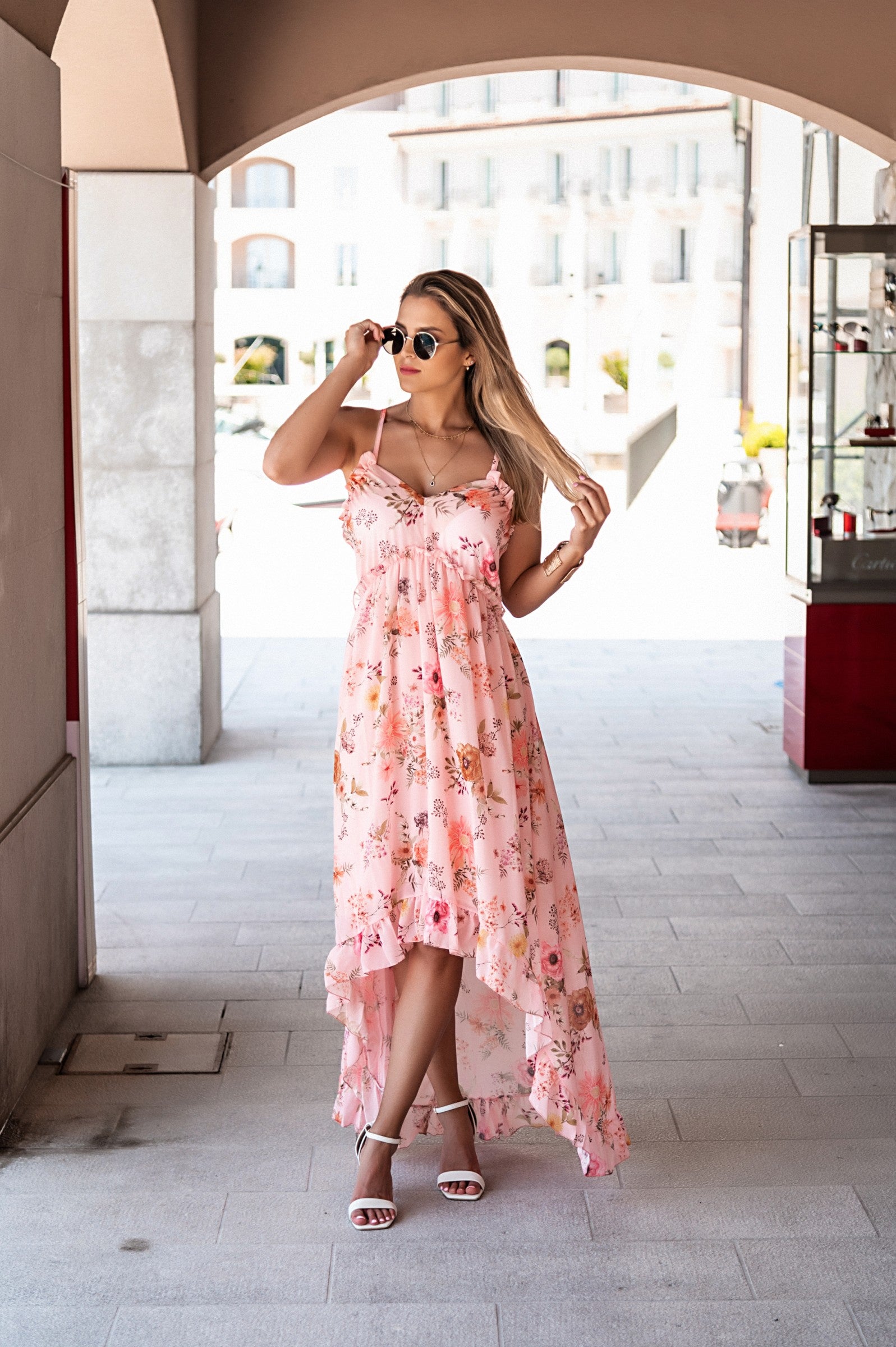 Elegant light pink maxi dress Noalla with print, featuring a plunging neckline, ruffle trim, and asymmetrical skirt with ruffles.