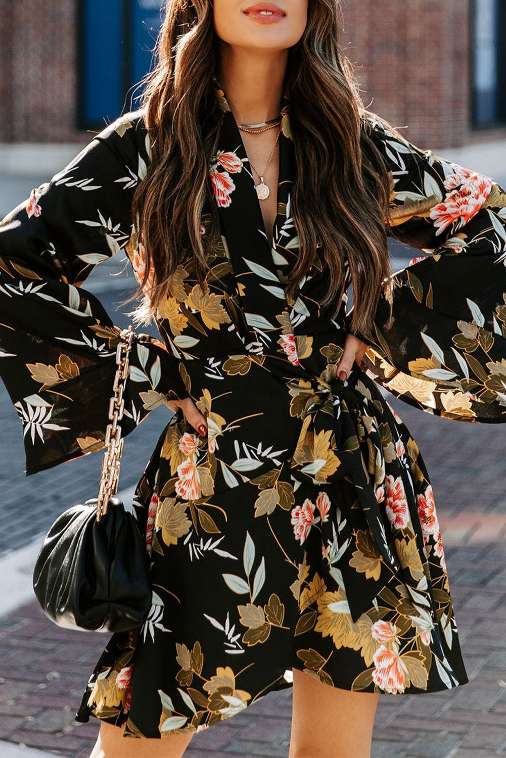 Elegant black mini dress featuring a floral print, wrap neckline, long ruffled sleeves, and a decorative belt.