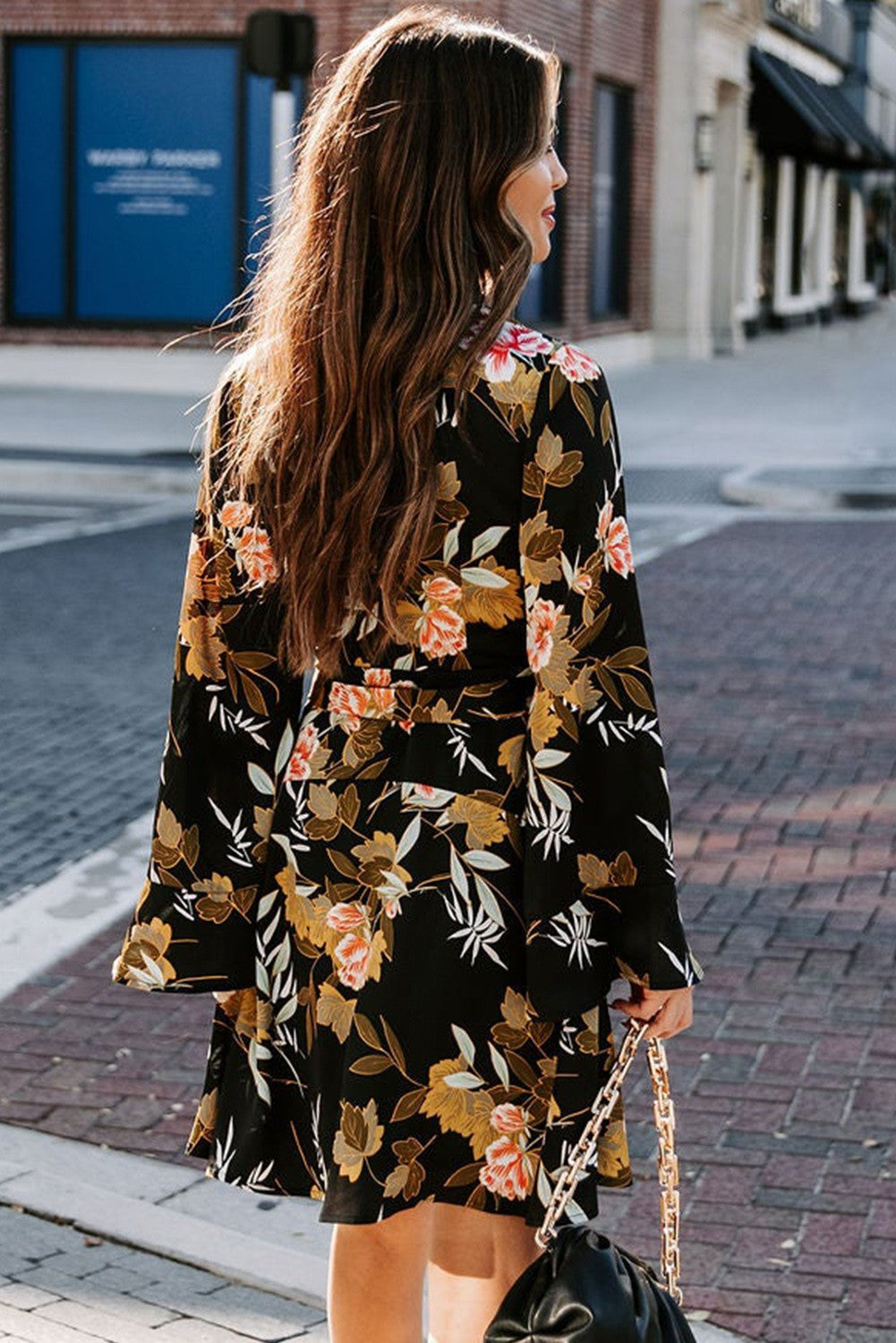 Elegant black mini dress featuring a floral print, wrap neckline, long ruffled sleeves, and a decorative belt.