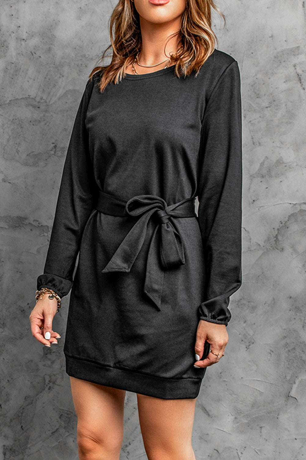 Elegant black mini dress with loose sleeves and a ribbon, showcasing a round neckline and mid-thigh length.