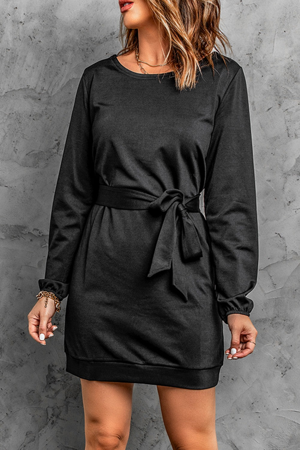 Elegant black mini dress with loose sleeves and a ribbon, showcasing a round neckline and mid-thigh length.