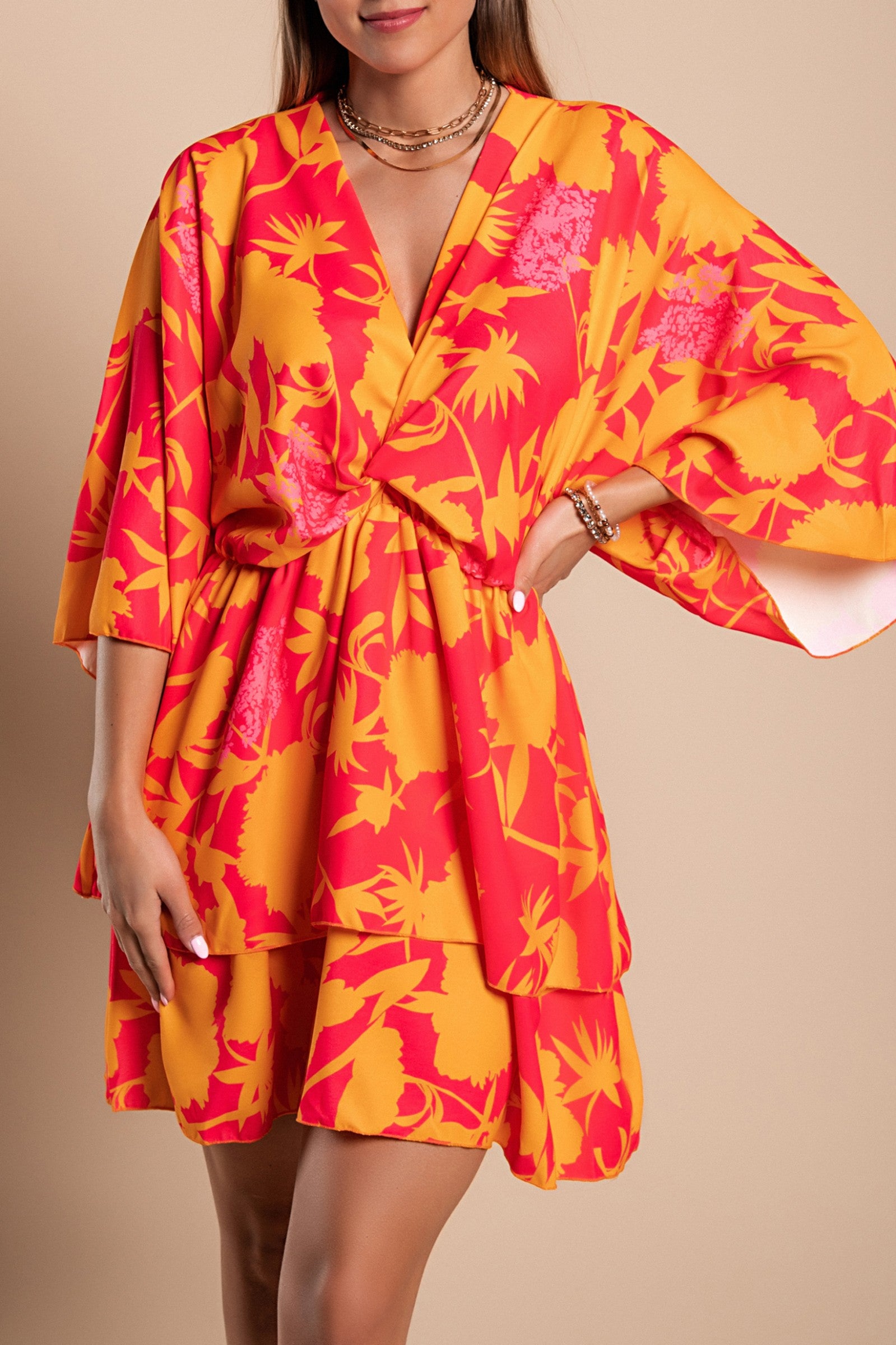 Elegant orange mini dress with print, featuring a deep neckline, loose sleeves, and ruffled skirt, made in Italy.