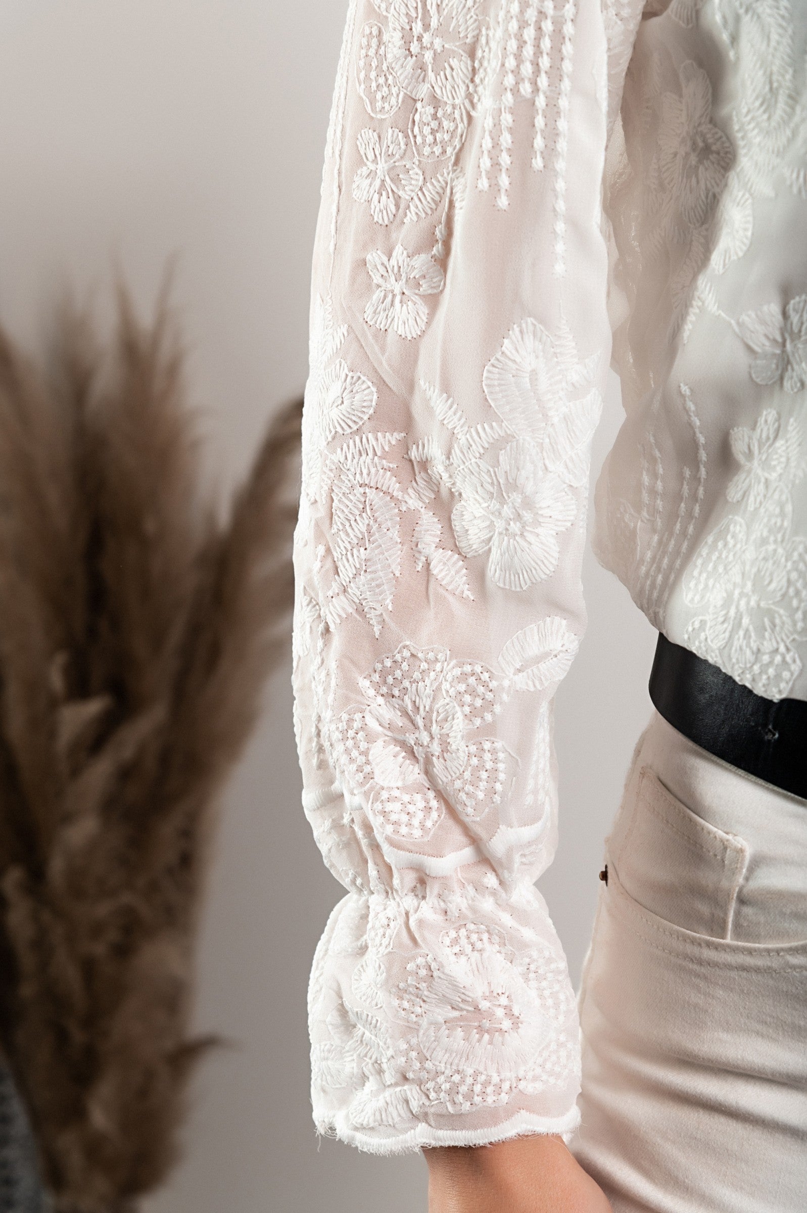 Elegant white shirt with embroidery and ruffles, featuring long sleeves and button closure.