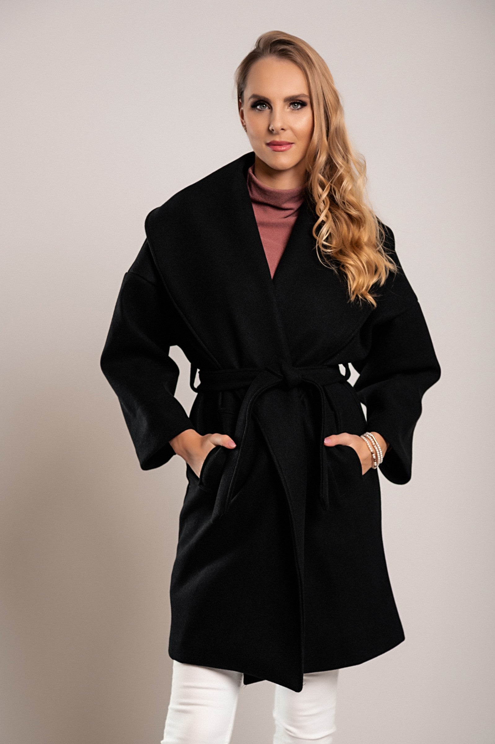 Elegant black short coat featuring a wide lapel collar and decorative belt, made from soft polyester fabric.