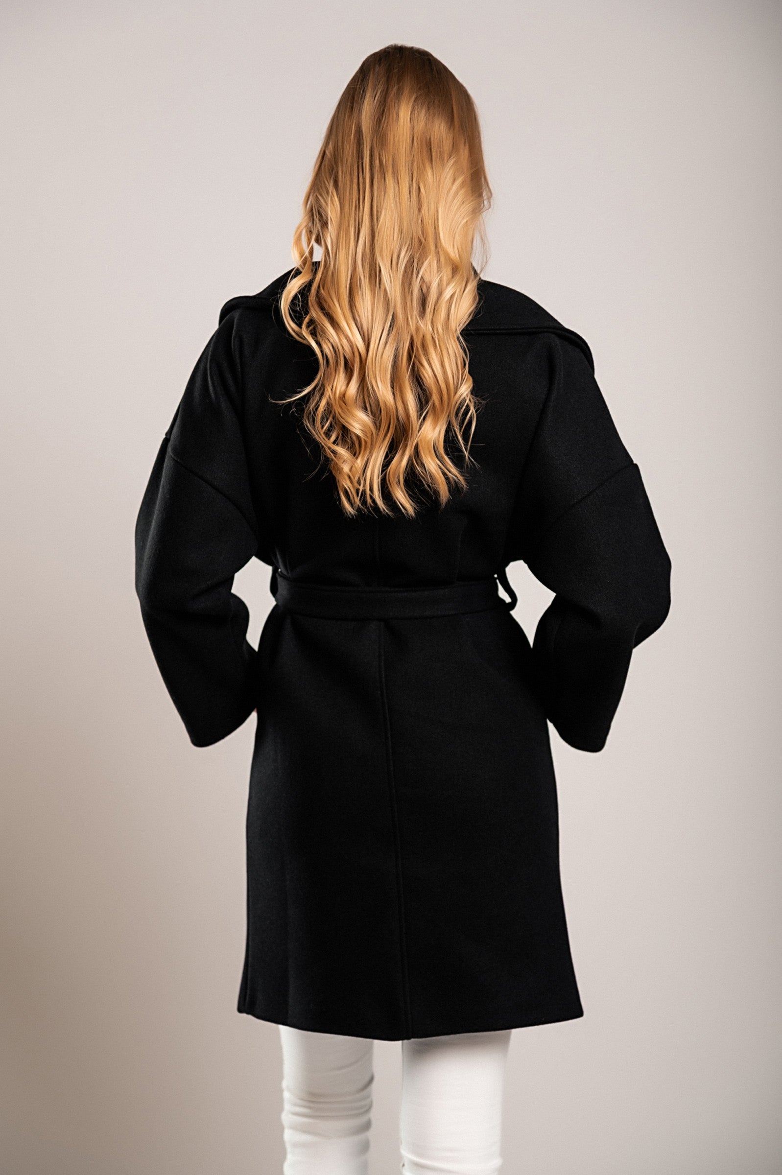 Elegant black short coat featuring a wide lapel collar and decorative belt, made from soft polyester fabric.