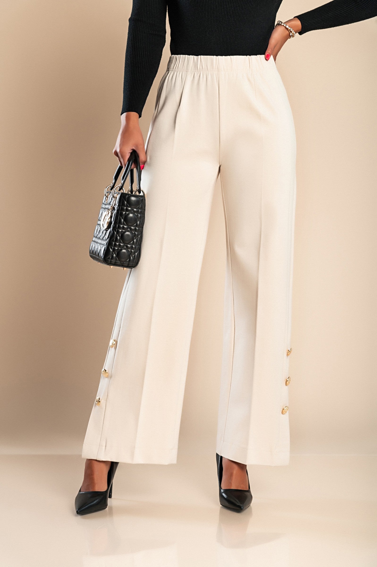 Elegant cream trousers with decorative buttons and elasticated waist, showcasing a stylish design suitable for various occasions.