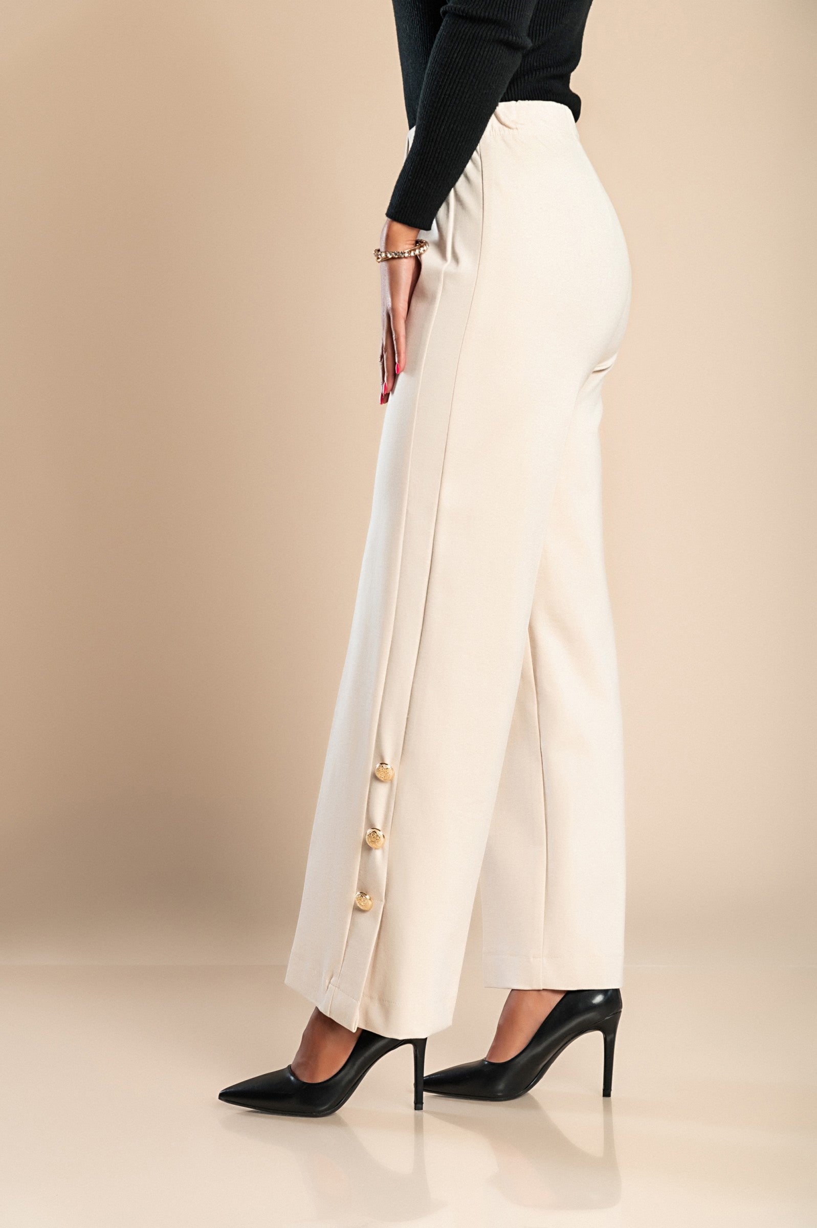 Elegant cream trousers with decorative buttons and elasticated waist, showcasing a stylish design suitable for various occasions.