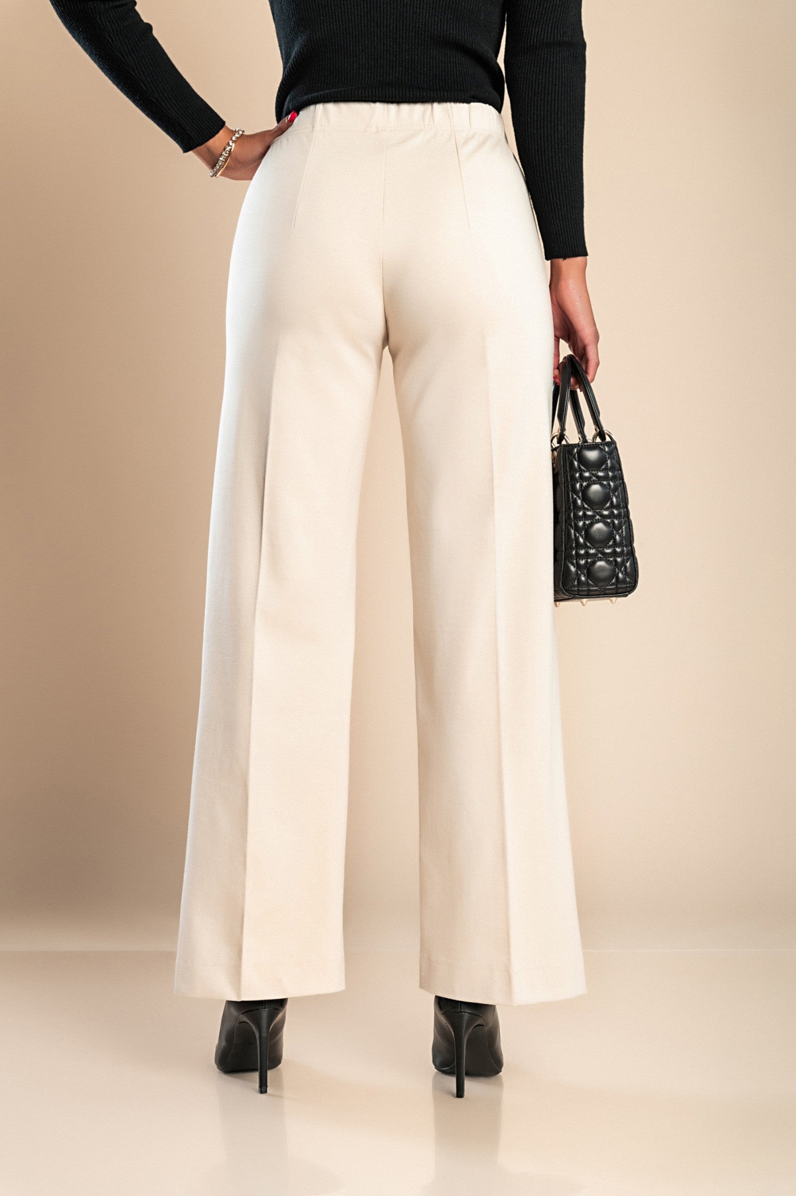 Elegant cream trousers with decorative buttons and elasticated waist, showcasing a stylish design suitable for various occasions.