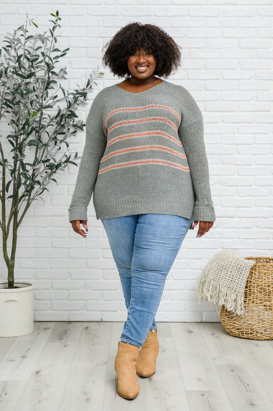 Eliza Striped Sweater featuring peach stripes on sage open-knit fabric, showcasing its lightweight and relaxed fit.