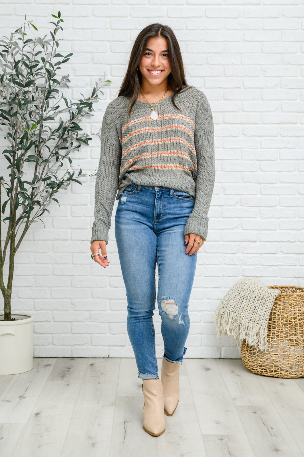 Eliza Striped Sweater featuring peach stripes on sage open-knit fabric, showcasing its lightweight and relaxed fit.