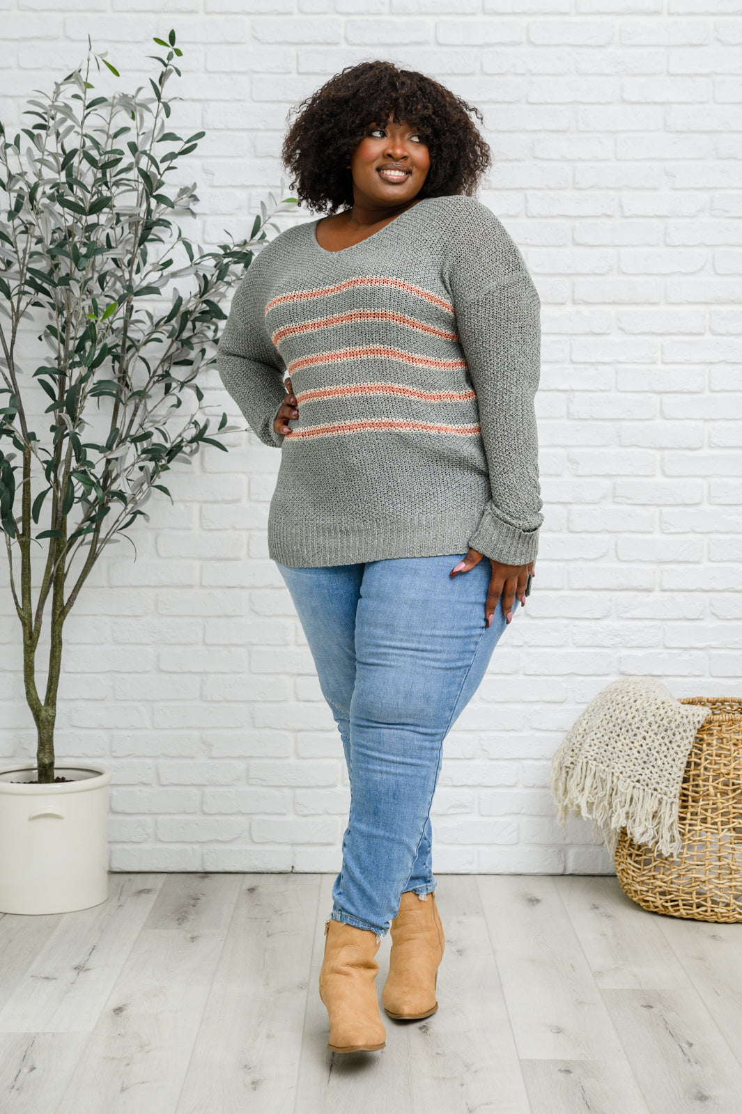 Eliza Striped Sweater featuring peach stripes on sage open-knit fabric, showcasing its lightweight and relaxed fit.