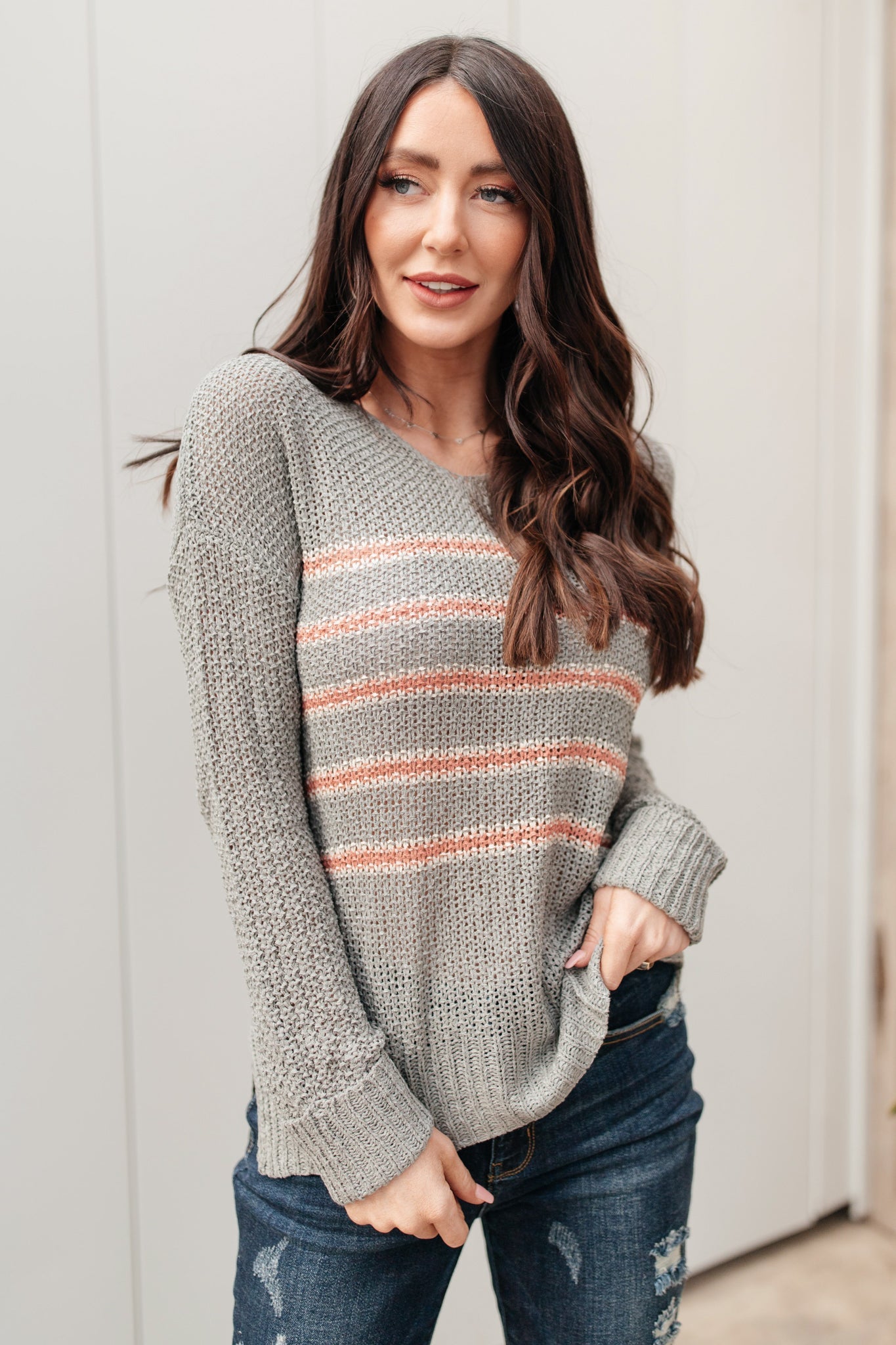 Eliza Striped Sweater featuring peach stripes on sage open-knit fabric, showcasing its lightweight and relaxed fit.