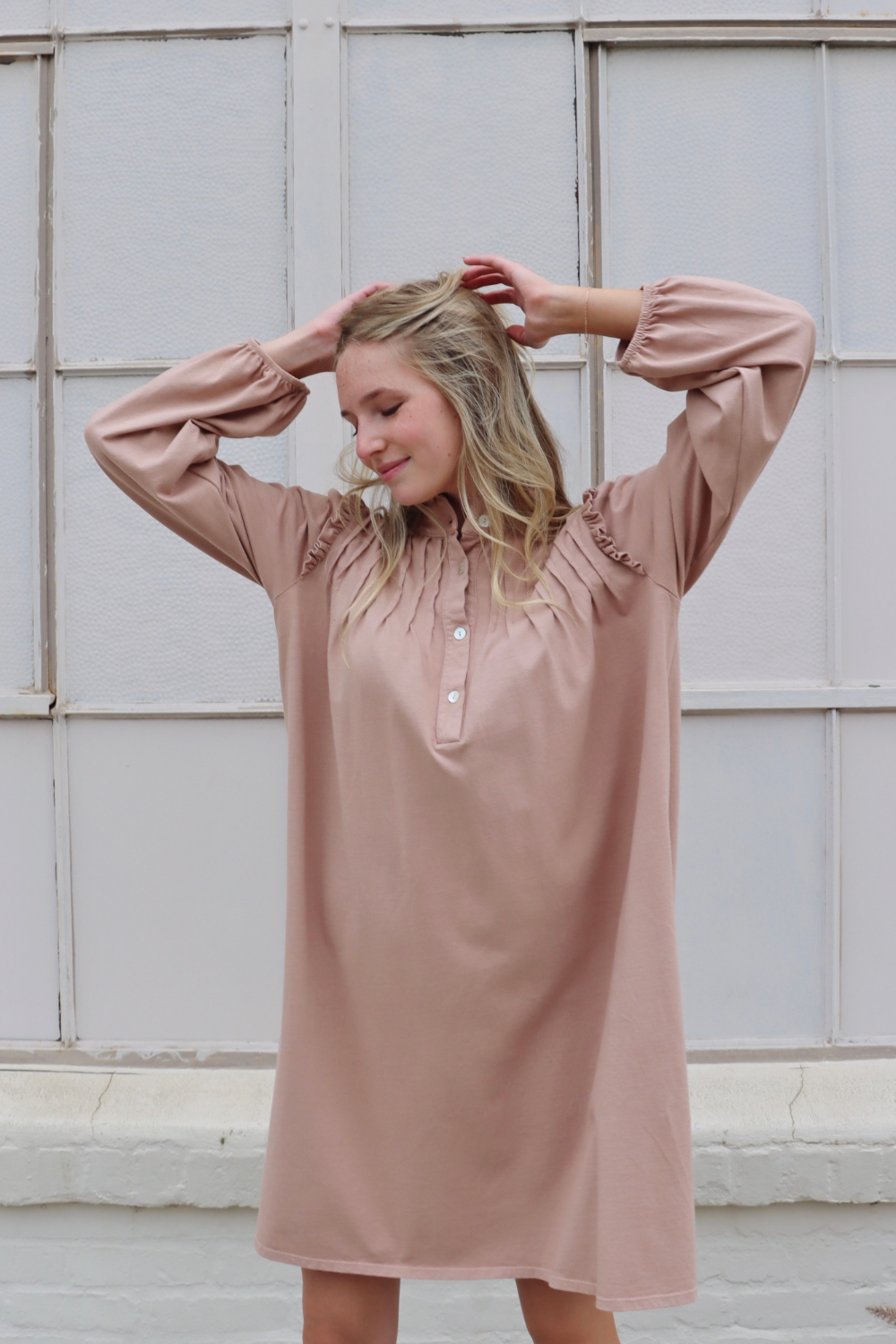 A stylish knee-length Embrace Dress featuring intricate neckline and shoulder details, made from 100% organic cotton in olive and rose pink colors.