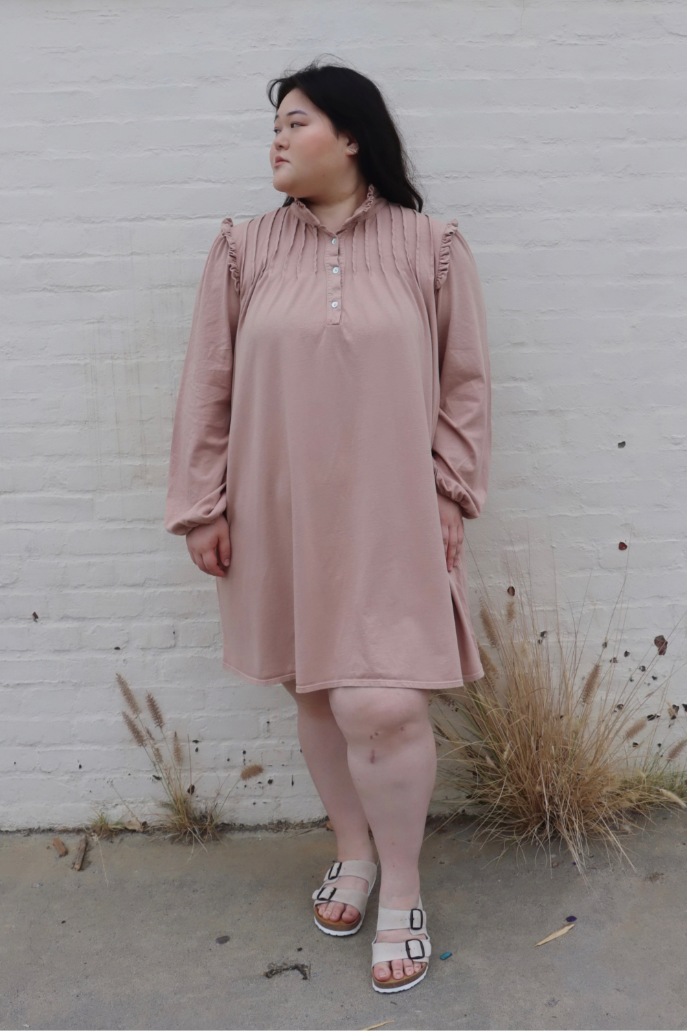 A stylish knee-length Embrace Dress featuring intricate neckline and shoulder details, made from 100% organic cotton in olive and rose pink colors.