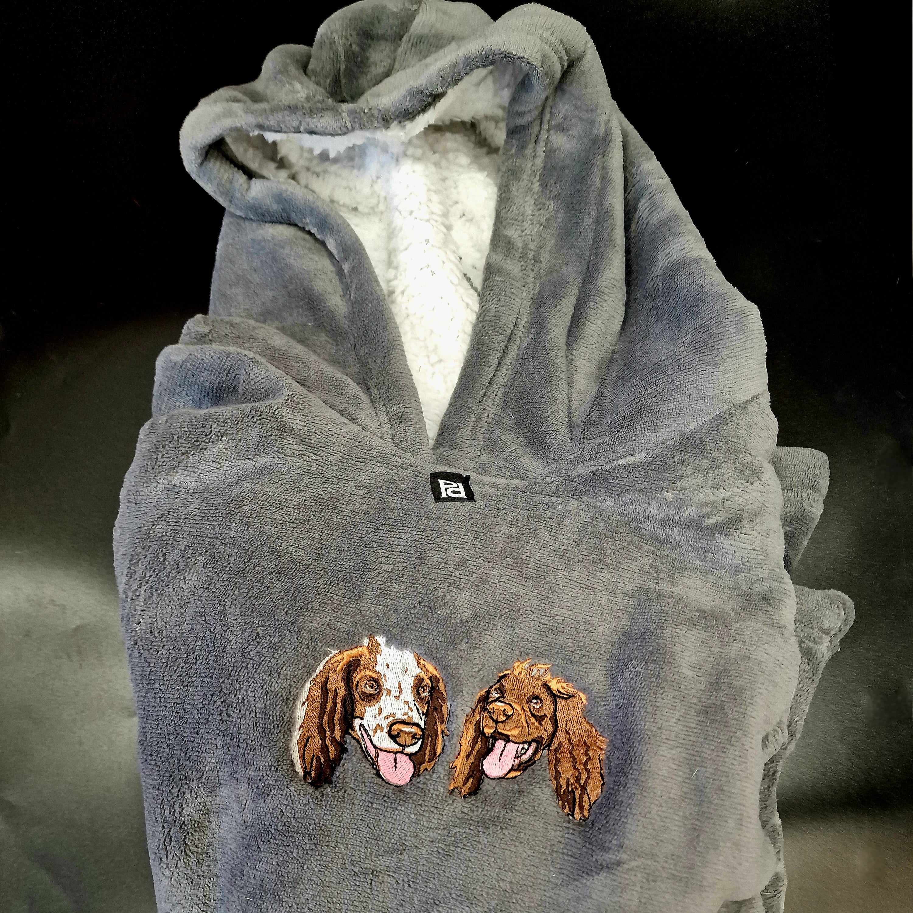 A cozy hooded blanket featuring a custom embroidered portrait of a pet, perfect for snuggling.