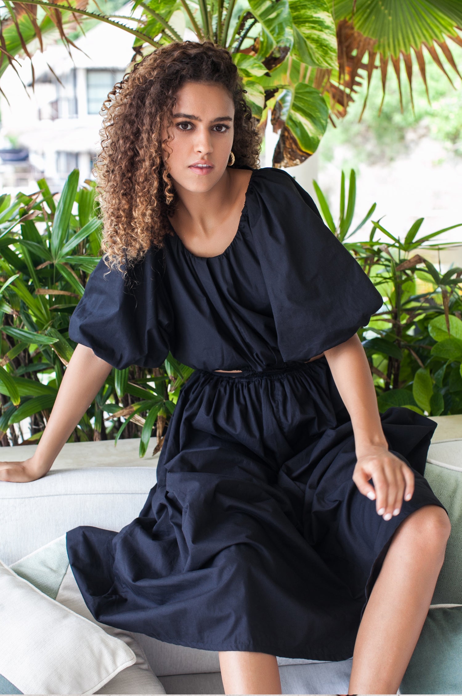 A stylish Eva Poplin Cotton Cutout Midi Dress featuring a voluminous skirt, puff sleeves, and elegant cutouts at the waist, available in multiple colors.