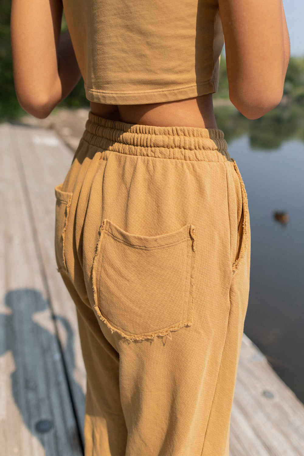 A pair of slouchy, cropped Everyday Pants in washed black with a drawstring waist and pockets, showcasing a relaxed fit and flared raw cut hem.