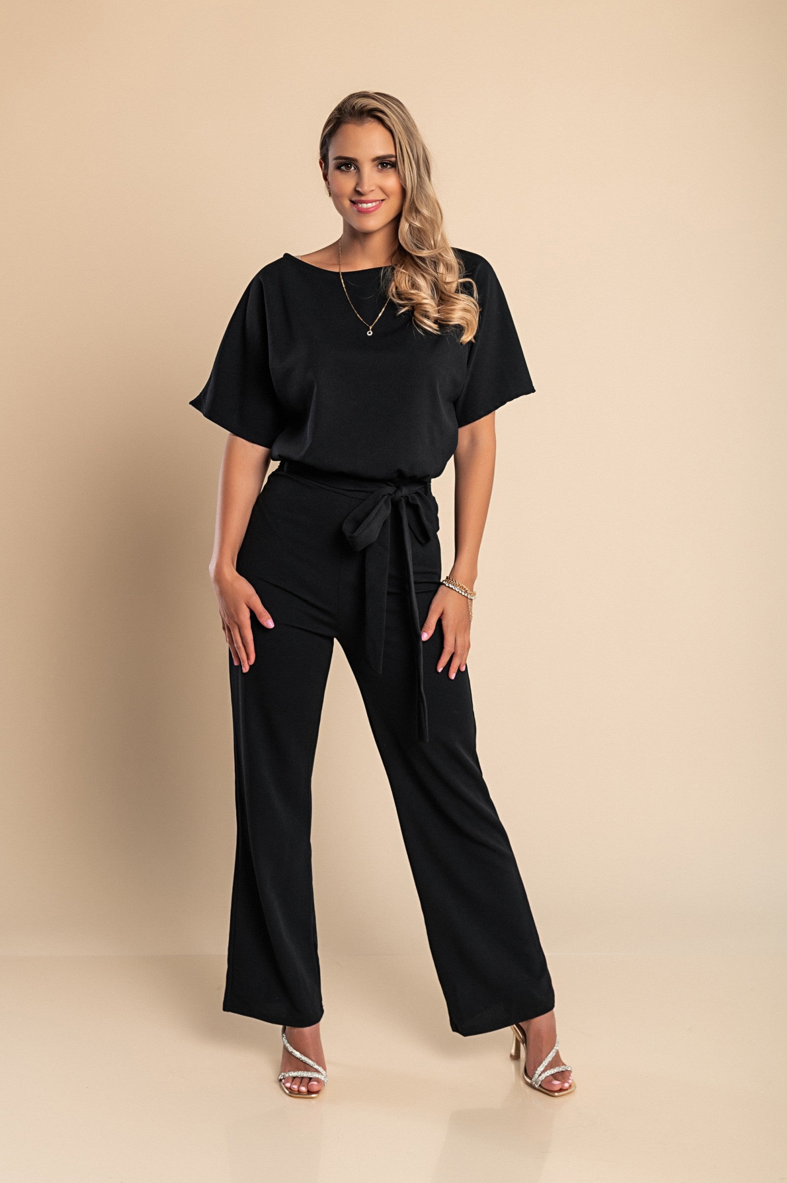 Black fashion jumpsuit with wide long pants and short sleeves, featuring a loose shirt and decorative belt.