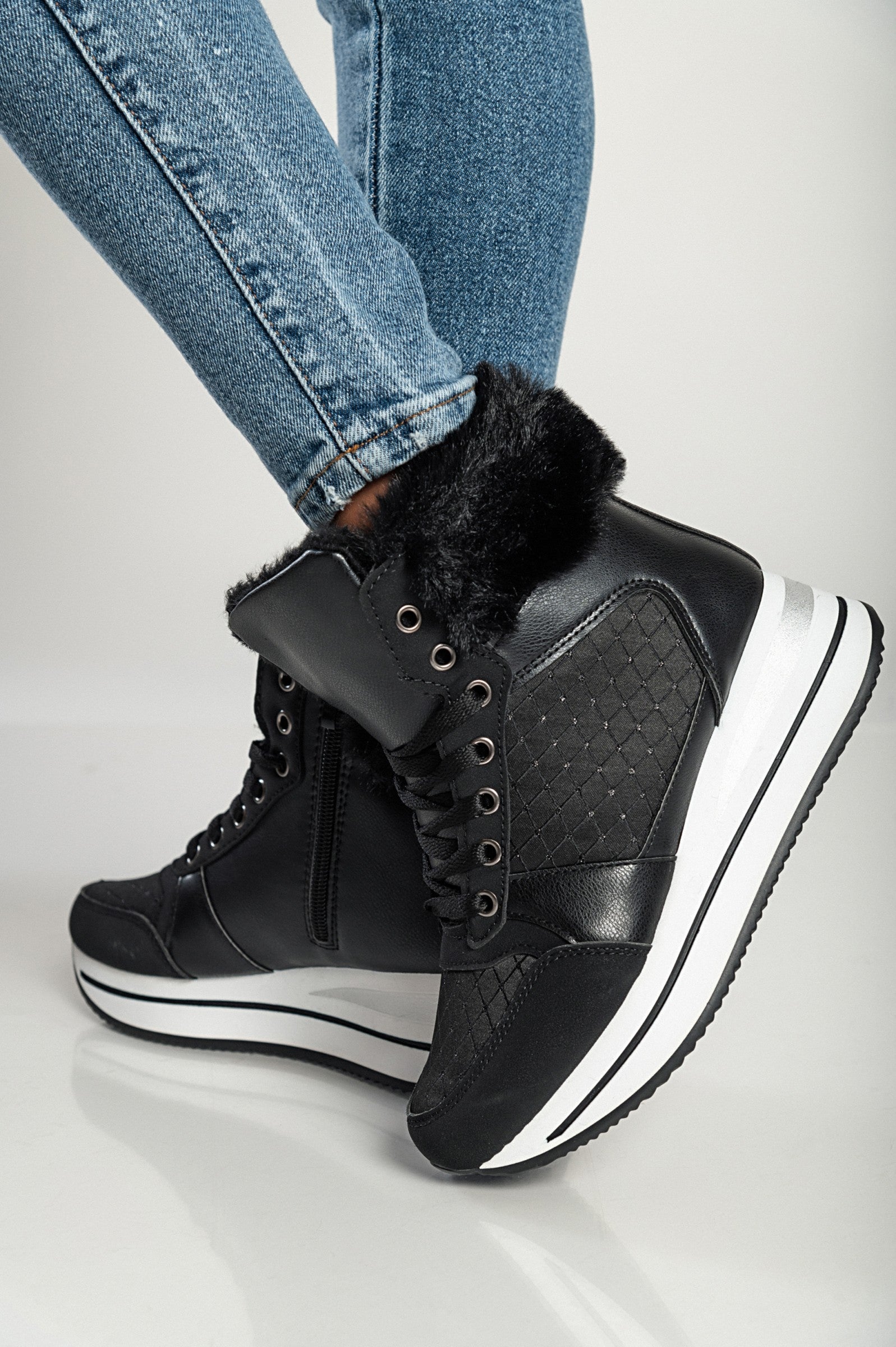 Black fashion sneakers made of faux leather and textile, featuring a raised sole, round toe, and lace-up closure with synthetic fur around the ankle.