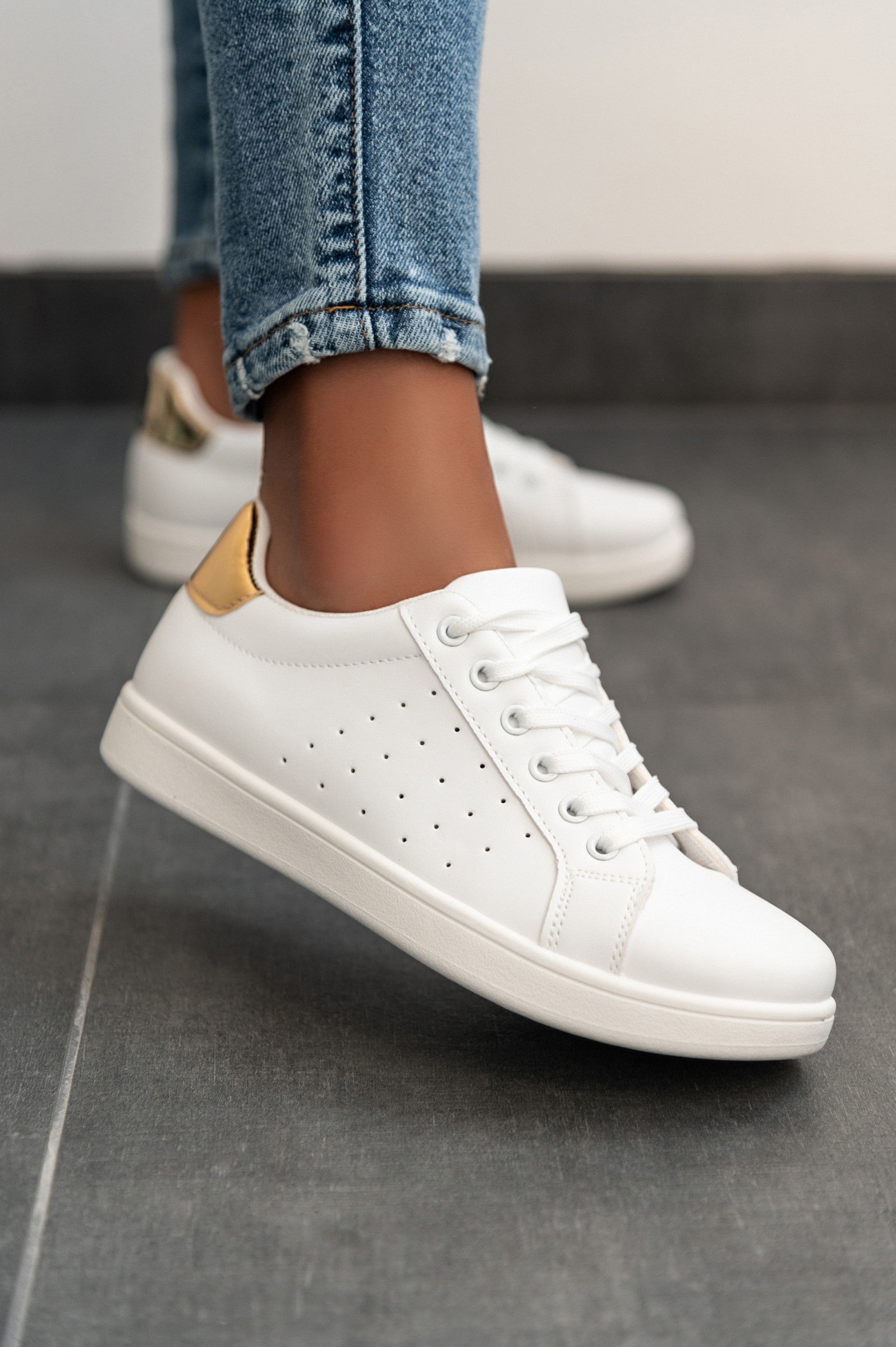 Stylish gold fashion sneakers with a flat sole and bow closure, showcasing a round toe design.