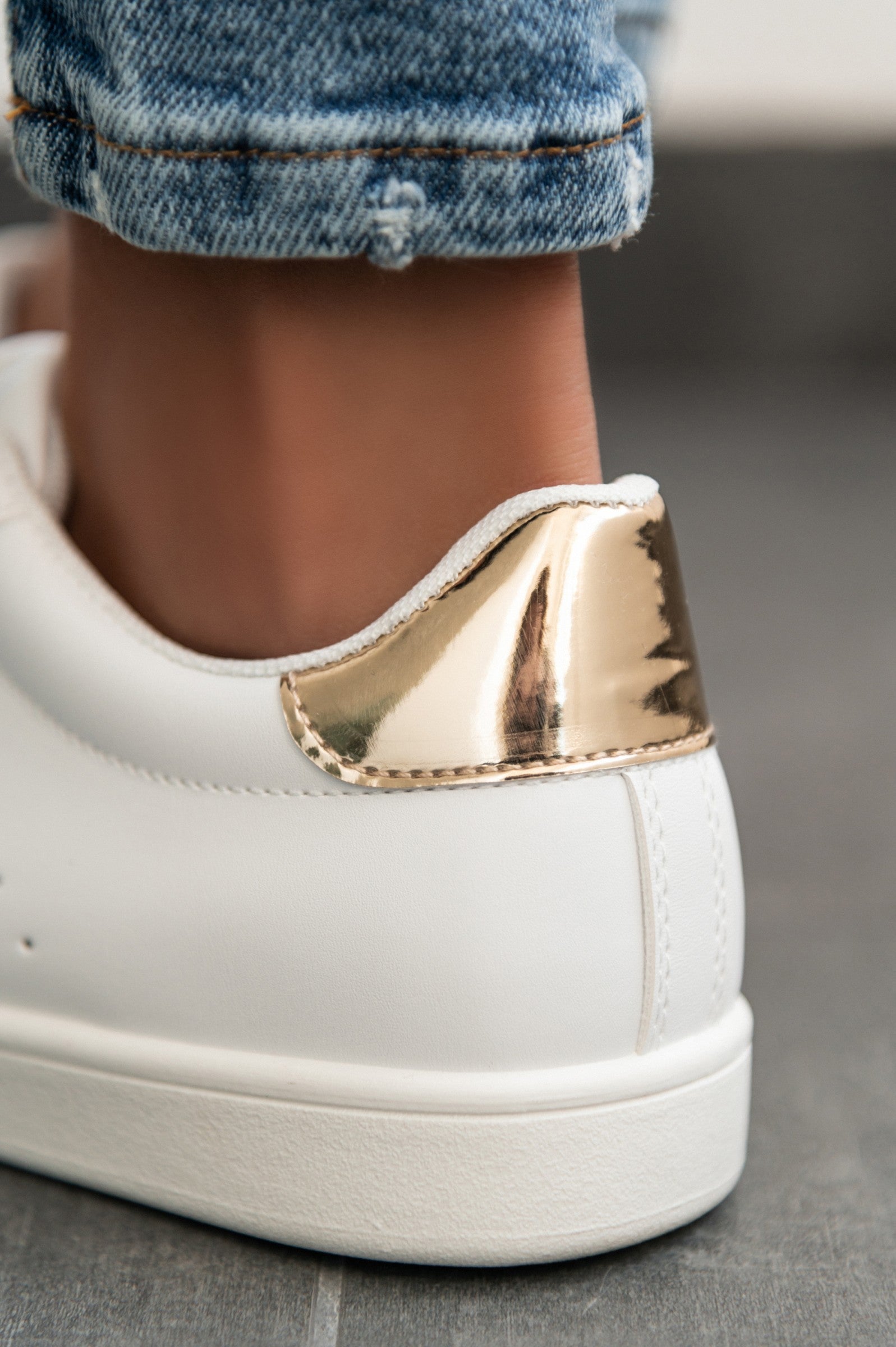 Stylish gold fashion sneakers with a flat sole and bow closure, showcasing a round toe design.