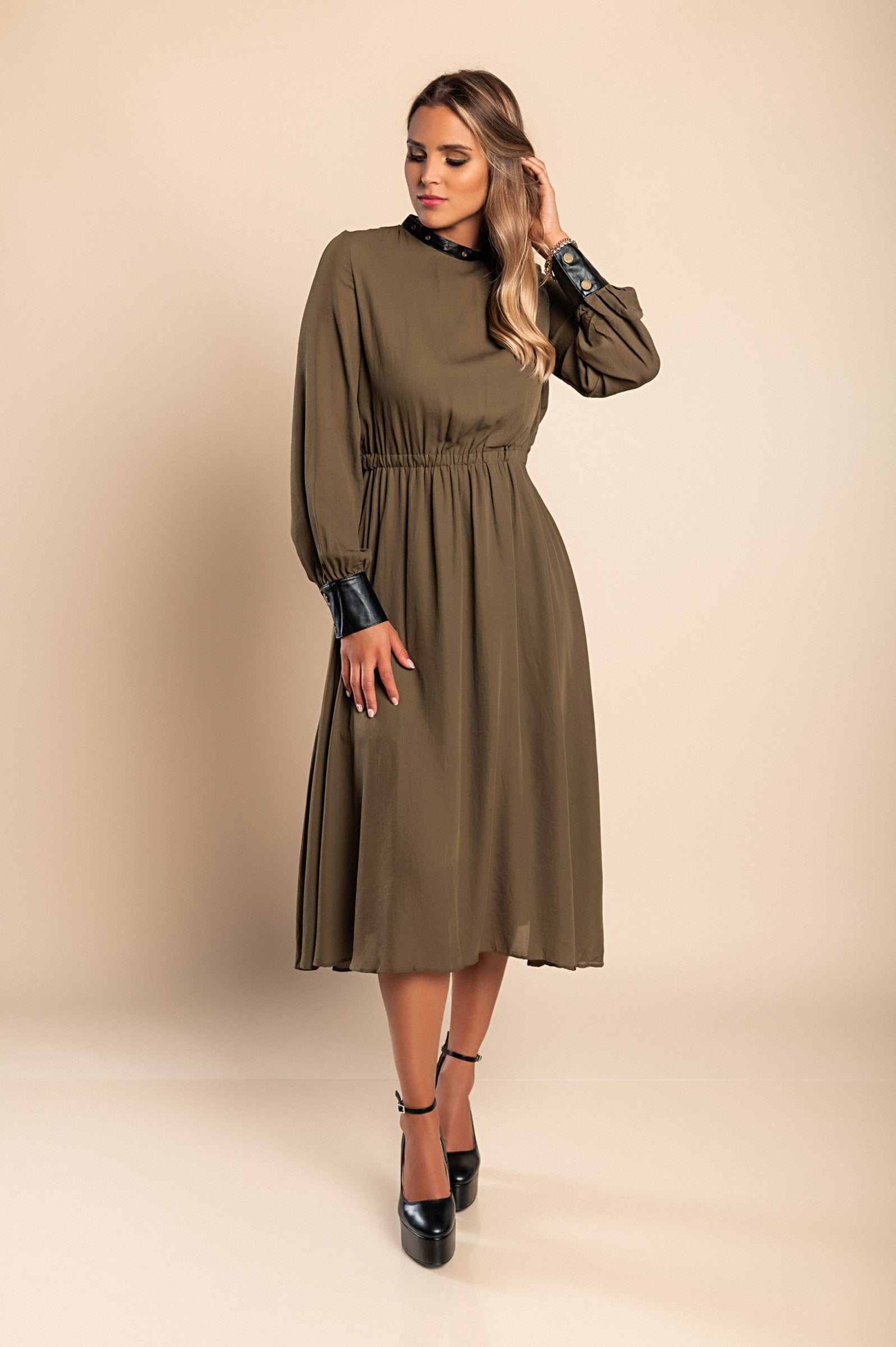 Olive green midi dress with faux leather details, featuring a round neckline, long sleeves, and an elastic waist, perfect for stylish occasions.