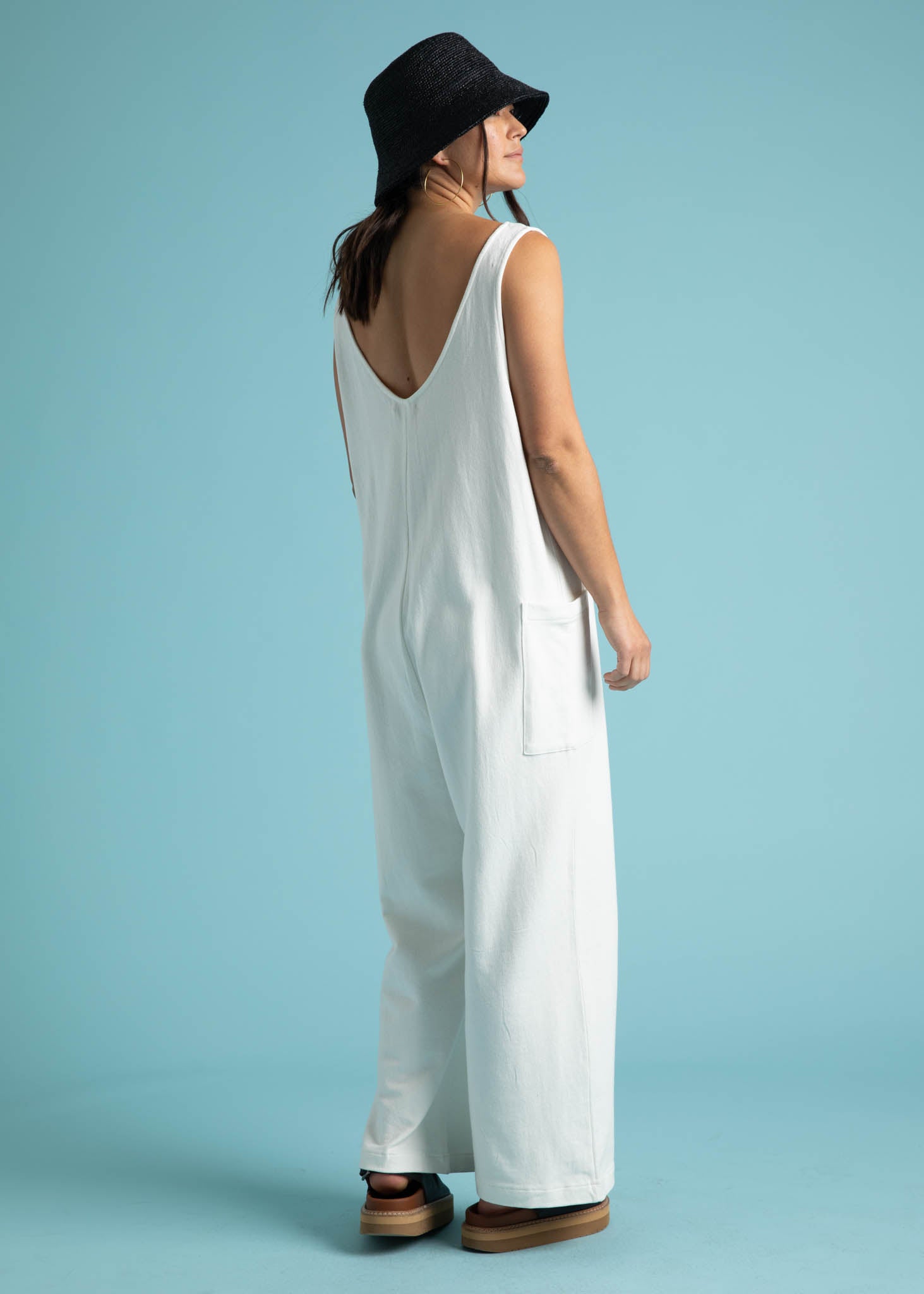 A stylish natural-colored Field Day Romper made from eco-friendly cotton jersey, featuring a relaxed fit, v-neck design, and patch side pockets.