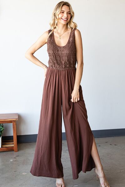 A stylish woman wearing the First Love Tie Back Sleeveless Slit Wide Leg Jumpsuit, showcasing its unique tie back design and flirty leg slit.