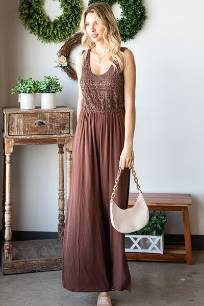 A stylish woman wearing the First Love Tie Back Sleeveless Slit Wide Leg Jumpsuit, showcasing its unique tie back design and flirty leg slit.