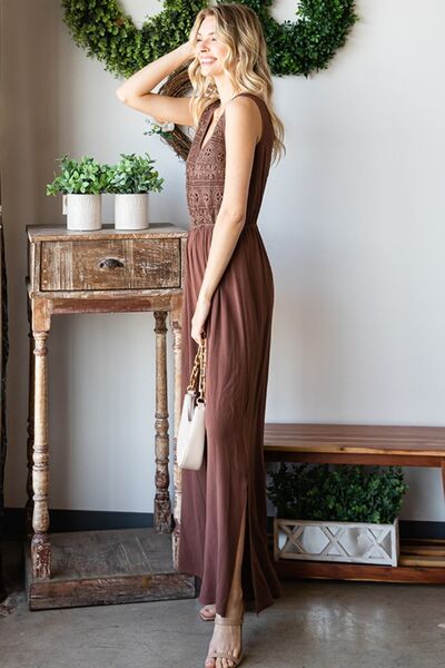 A stylish woman wearing the First Love Tie Back Sleeveless Slit Wide Leg Jumpsuit, showcasing its unique tie back design and flirty leg slit.