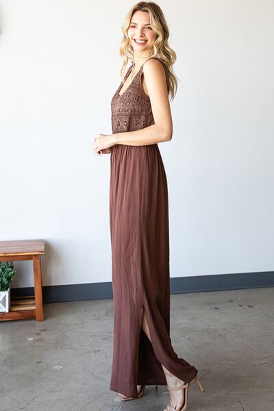 A stylish woman wearing the First Love Tie Back Sleeveless Slit Wide Leg Jumpsuit, showcasing its unique tie back design and flirty leg slit.