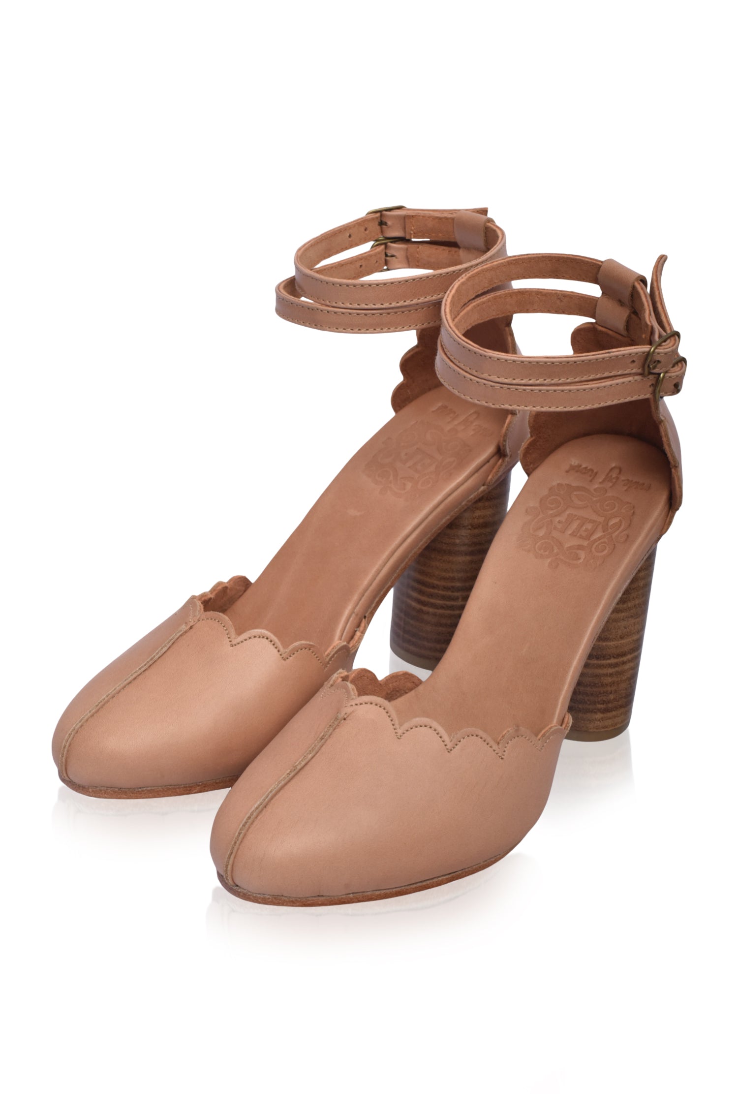 A pair of elegant Flamingo Leather Heels featuring a closed toe design, dual ankle straps, and a hand-cut wooden heel, showcasing their luxurious leather finish.