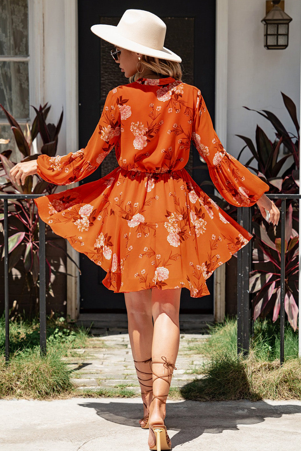 A stylish Floral Buttoned Puff Sleeve Tiered Dress featuring a floral pattern, balloon sleeves, and a mini length, displayed outdoors in a flat lay style.