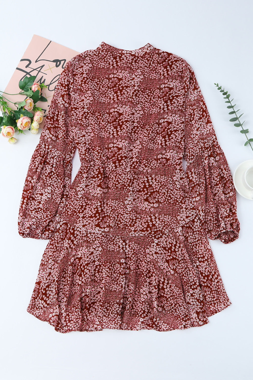 A stylish Floral Buttoned Puff Sleeve Tiered Dress featuring a floral pattern, balloon sleeves, and a mini length, displayed outdoors in a flat lay style.