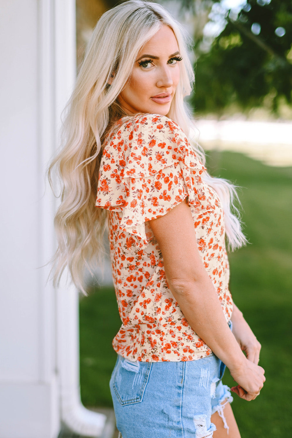 A stylish Floral Tiered Flutter Sleeve Blouse featuring a vibrant floral pattern, flutter sleeves, and a classic crew neckline, perfect for sunny days.