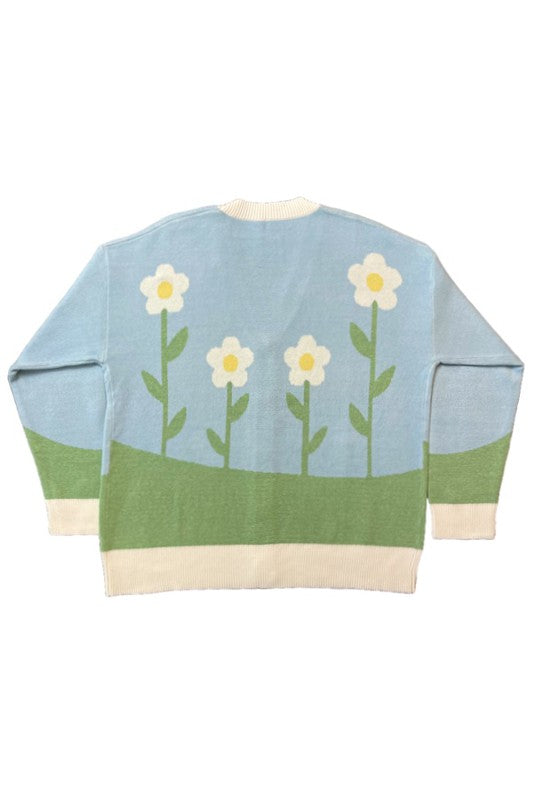 A stylish Flower Field Knit Cardigan featuring a vibrant flower field and sun intarsia design, button front, and V neckline.