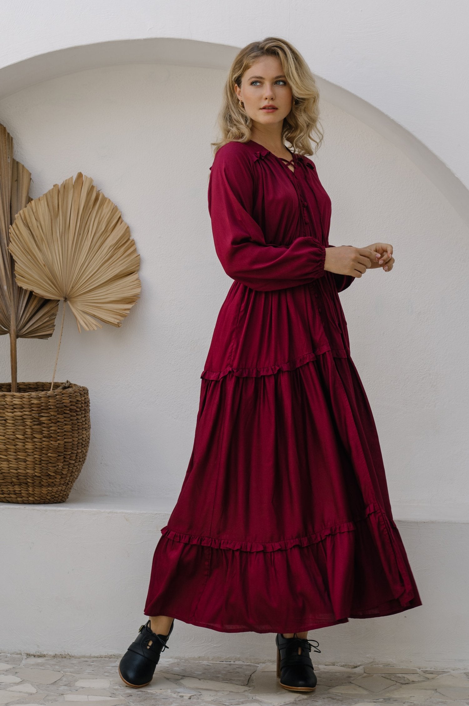 A beautiful woman wearing the Flower Fields Maxi Dress, showcasing its V-neckline, ruffle details, and vibrant floral pattern.