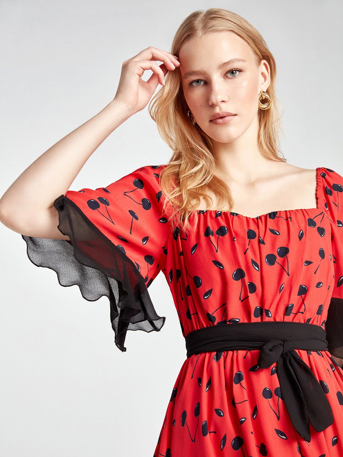 A stylish Flowy Mini Dress featuring ruffled sleeves, an elastic waistband, and a belt, perfect for spring occasions.