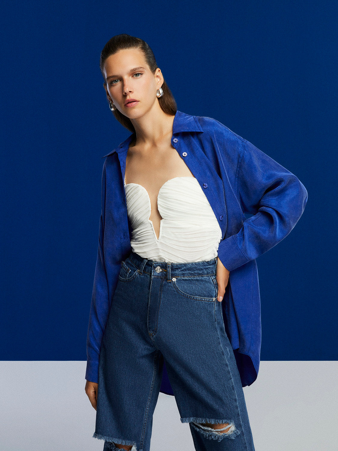 Flowy oversized shirt with lapel collar, front buttons, and long sleeves, featuring vibrant colors and a relaxed fit.