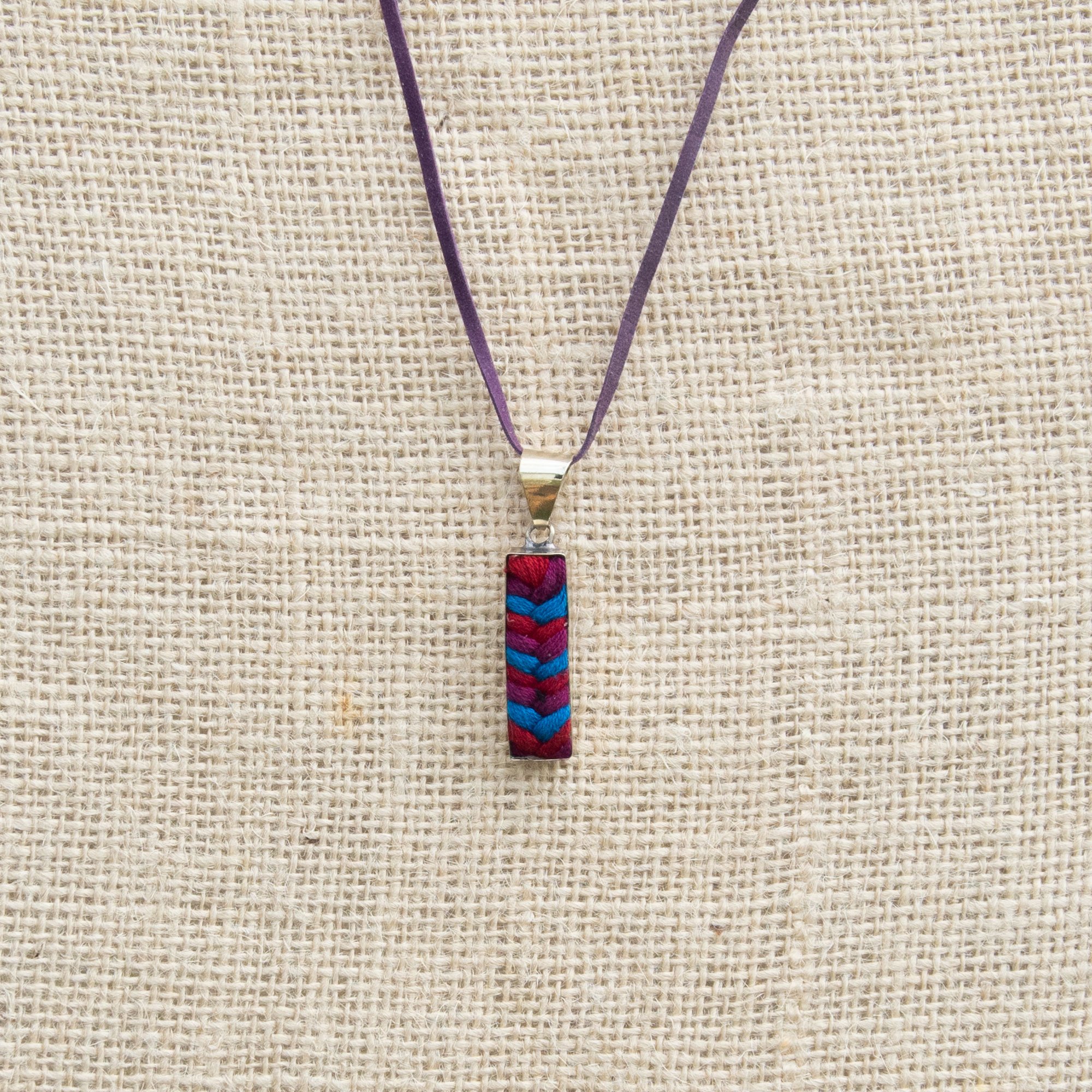 A colorful Folk Long Pendant Necklace featuring unique hand-embroidered patterns by artisans from Chiapas, Mexico, displayed elegantly on a neutral background.