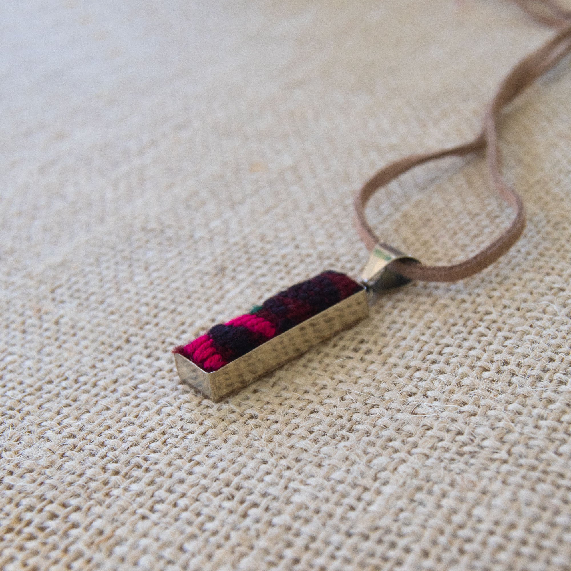 A colorful Folk Long Pendant Necklace featuring unique hand-embroidered patterns by artisans from Chiapas, Mexico, displayed elegantly on a neutral background.