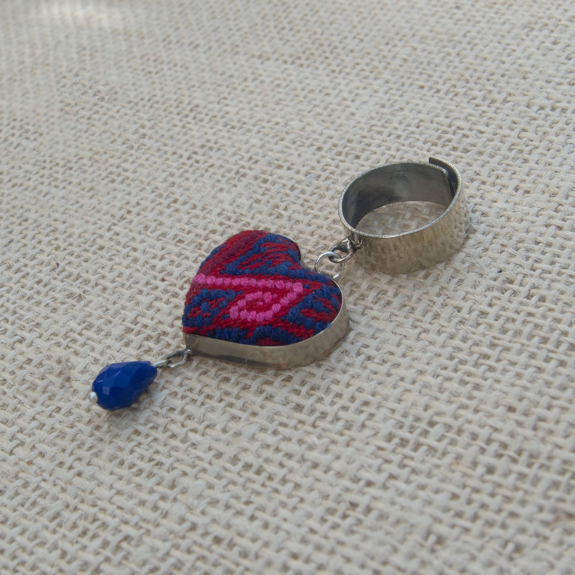 Folk Ring featuring a hanging heart pendant and colorful embroidered textile, handcrafted in Chiapas, Mexico.