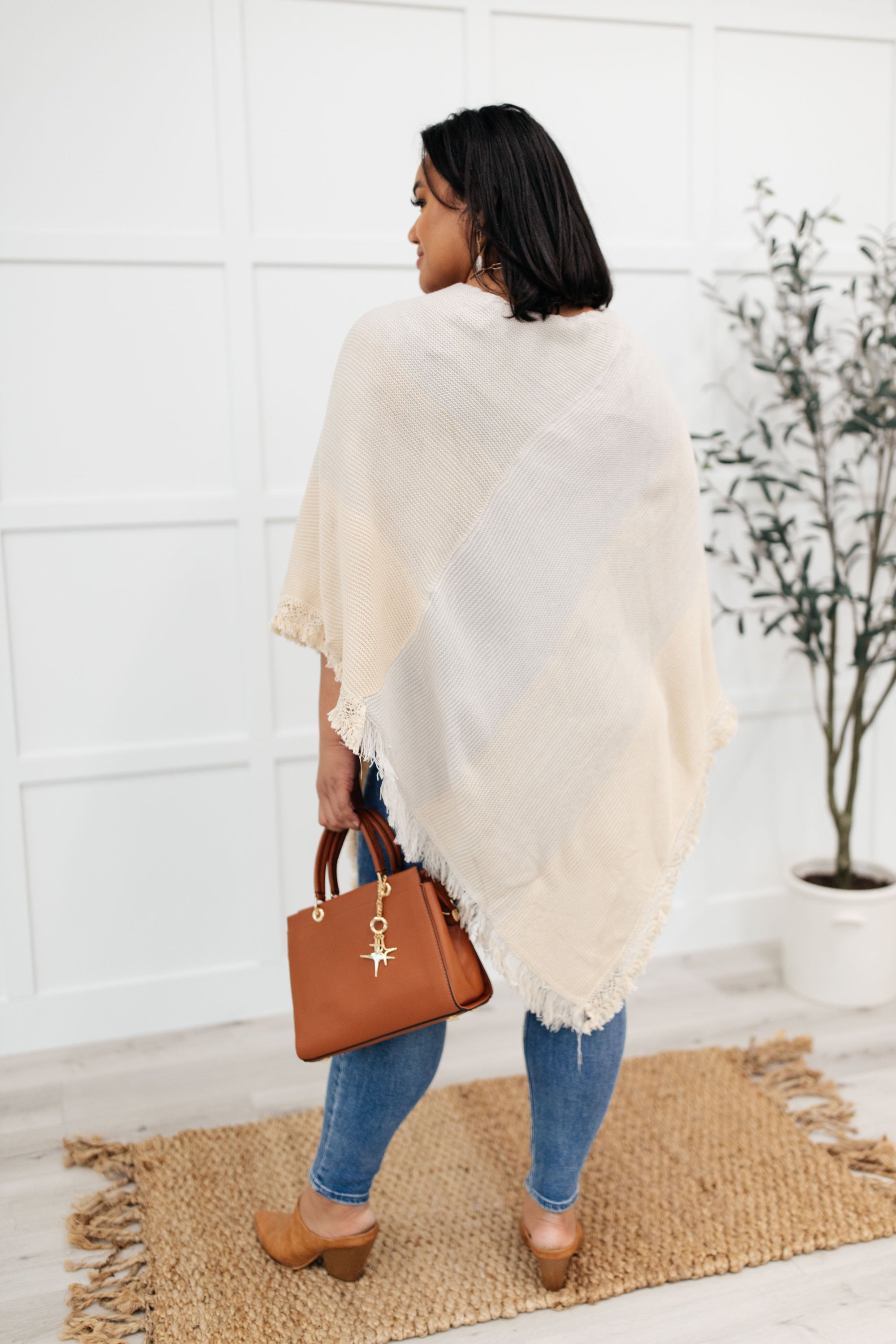 A stylish grey poncho with a color-blocked design and fringed edges, perfect for chilly days and cozy movie nights.