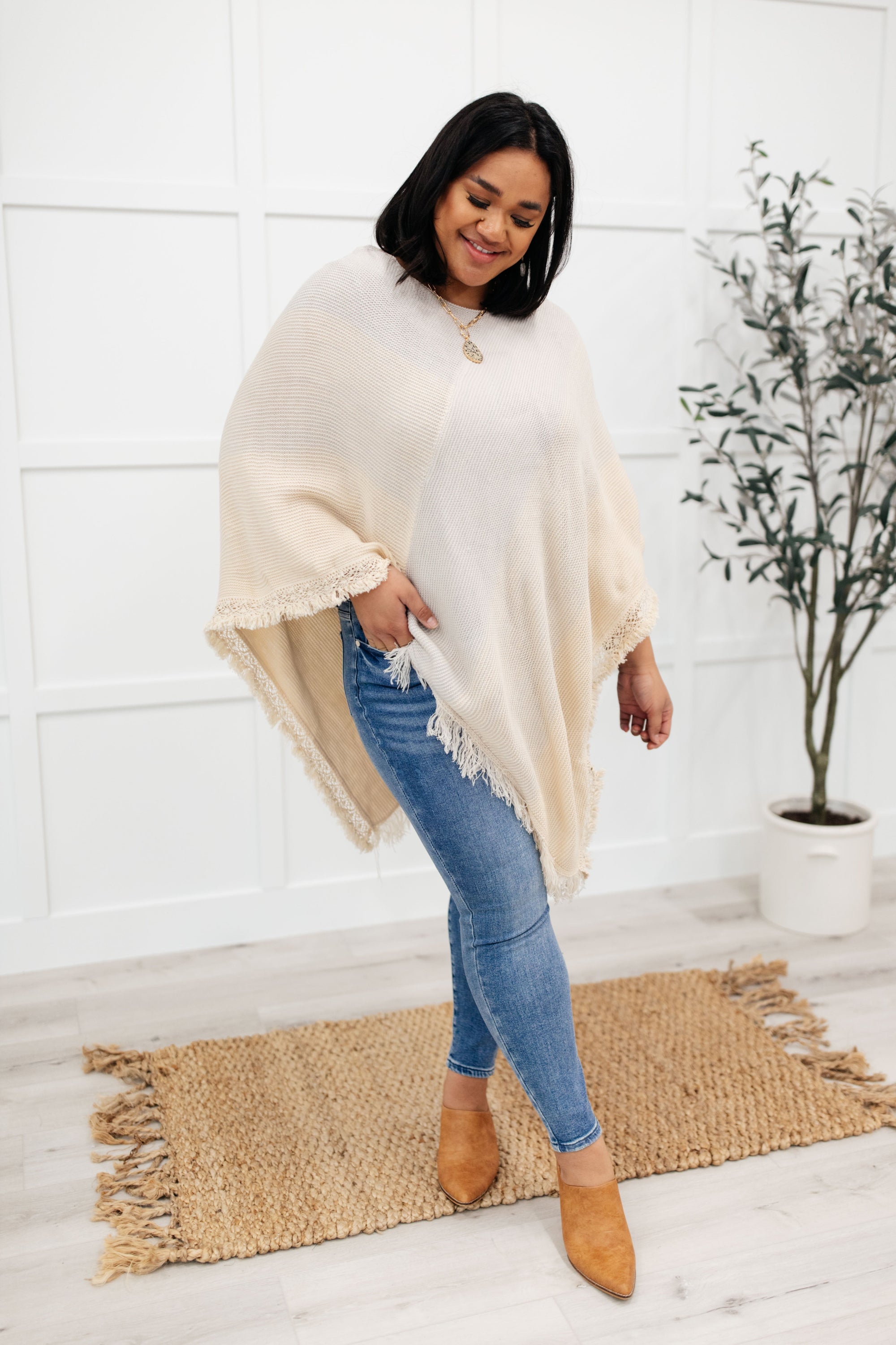 A stylish grey poncho with a color-blocked design and fringed edges, perfect for chilly days and cozy movie nights.