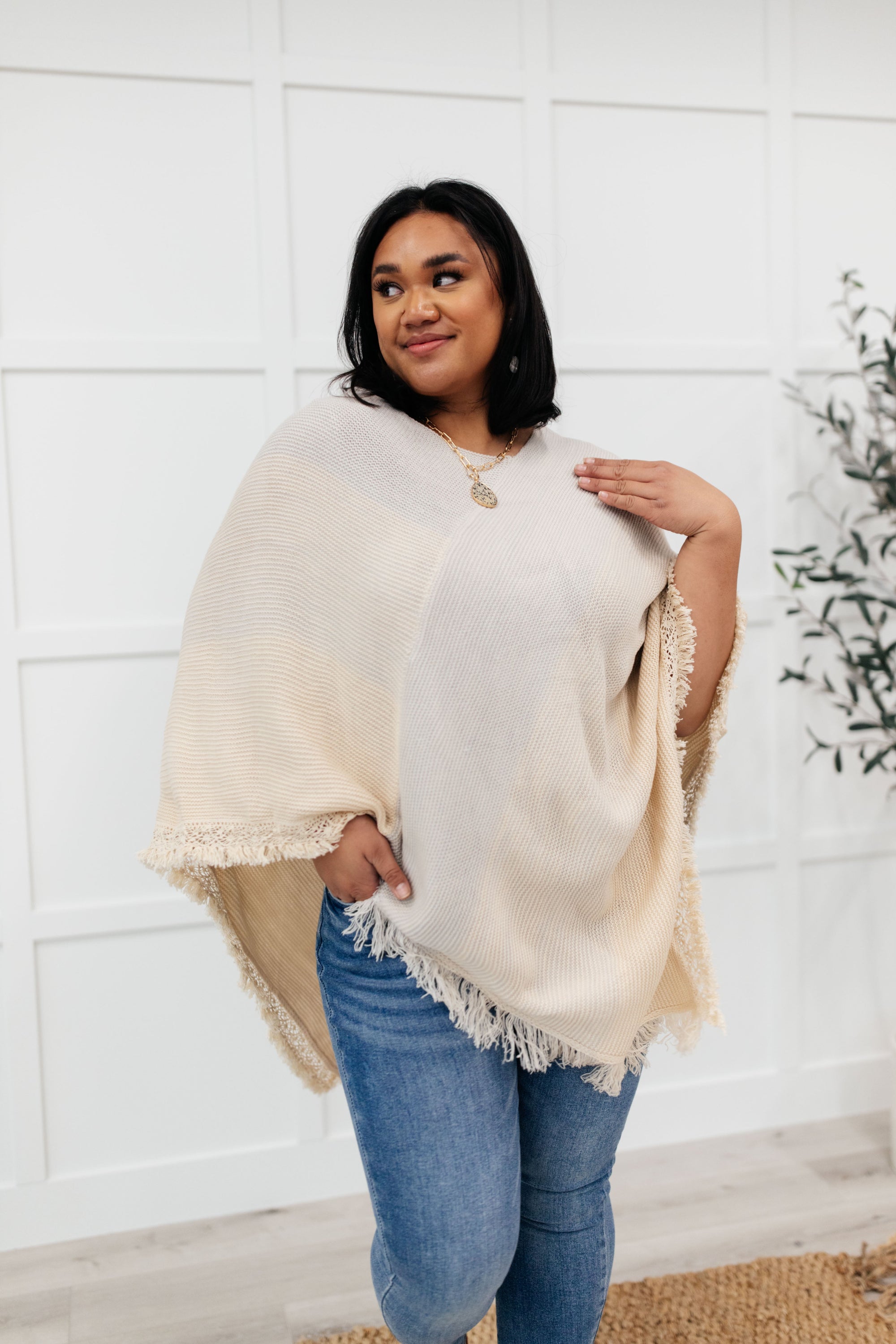 A stylish grey poncho with a color-blocked design and fringed edges, perfect for chilly days and cozy movie nights.