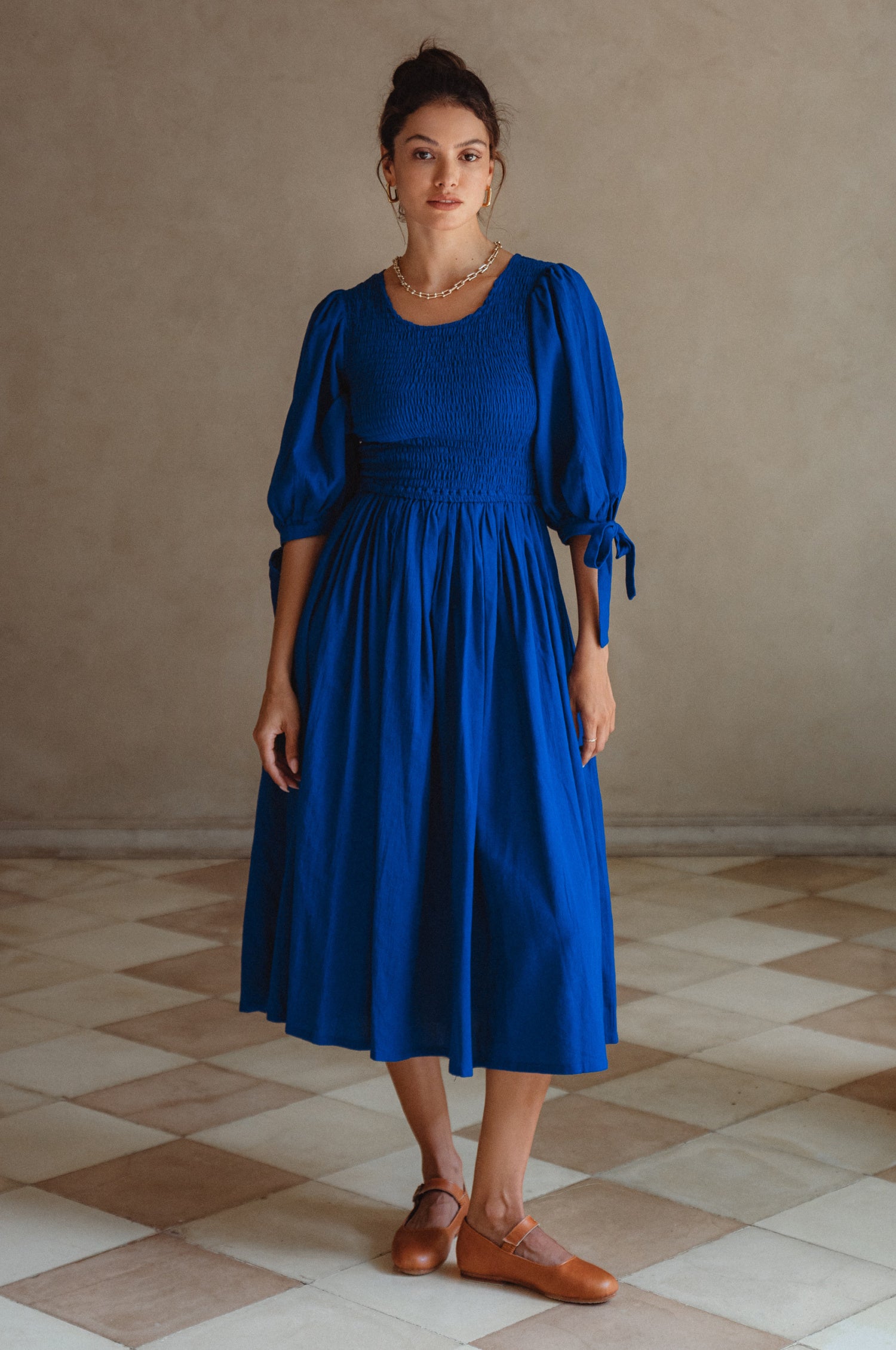 Freya Smocked Linen Midi Dress featuring a smocked bodice and tie-up puffy sleeves in a light crinkle linen fabric.