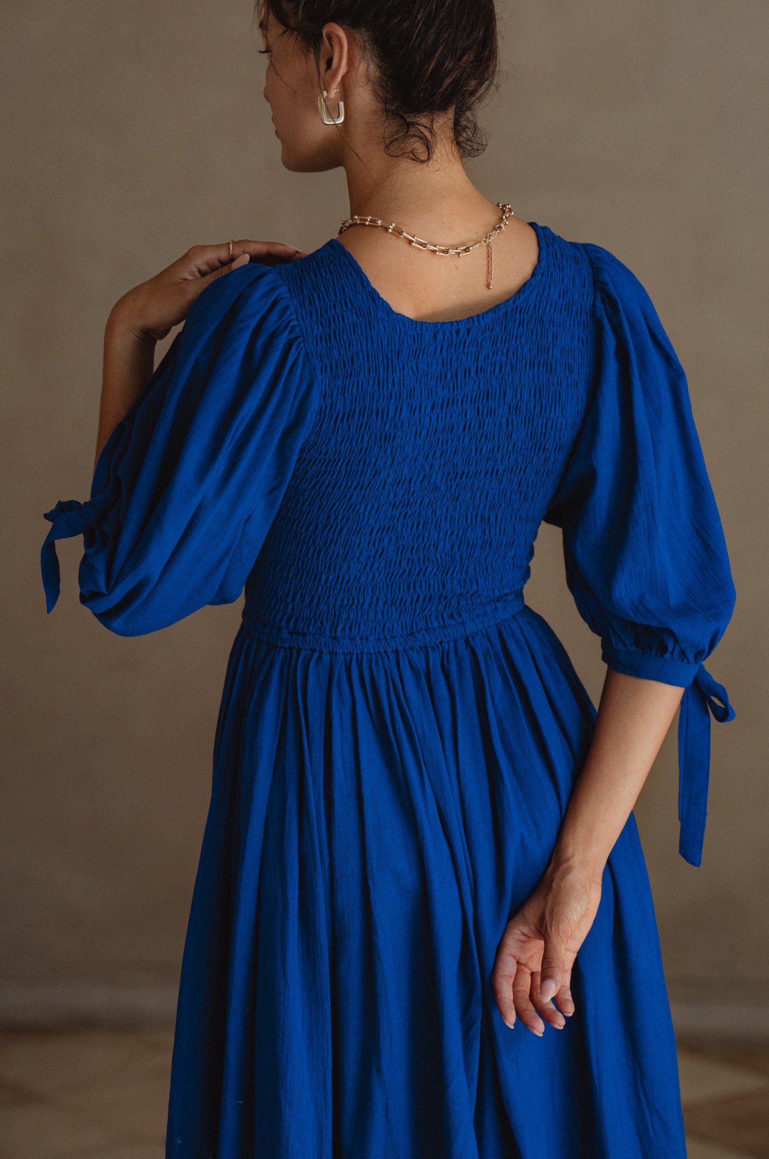 Freya Smocked Linen Midi Dress featuring a smocked bodice and tie-up puffy sleeves in a light crinkle linen fabric.