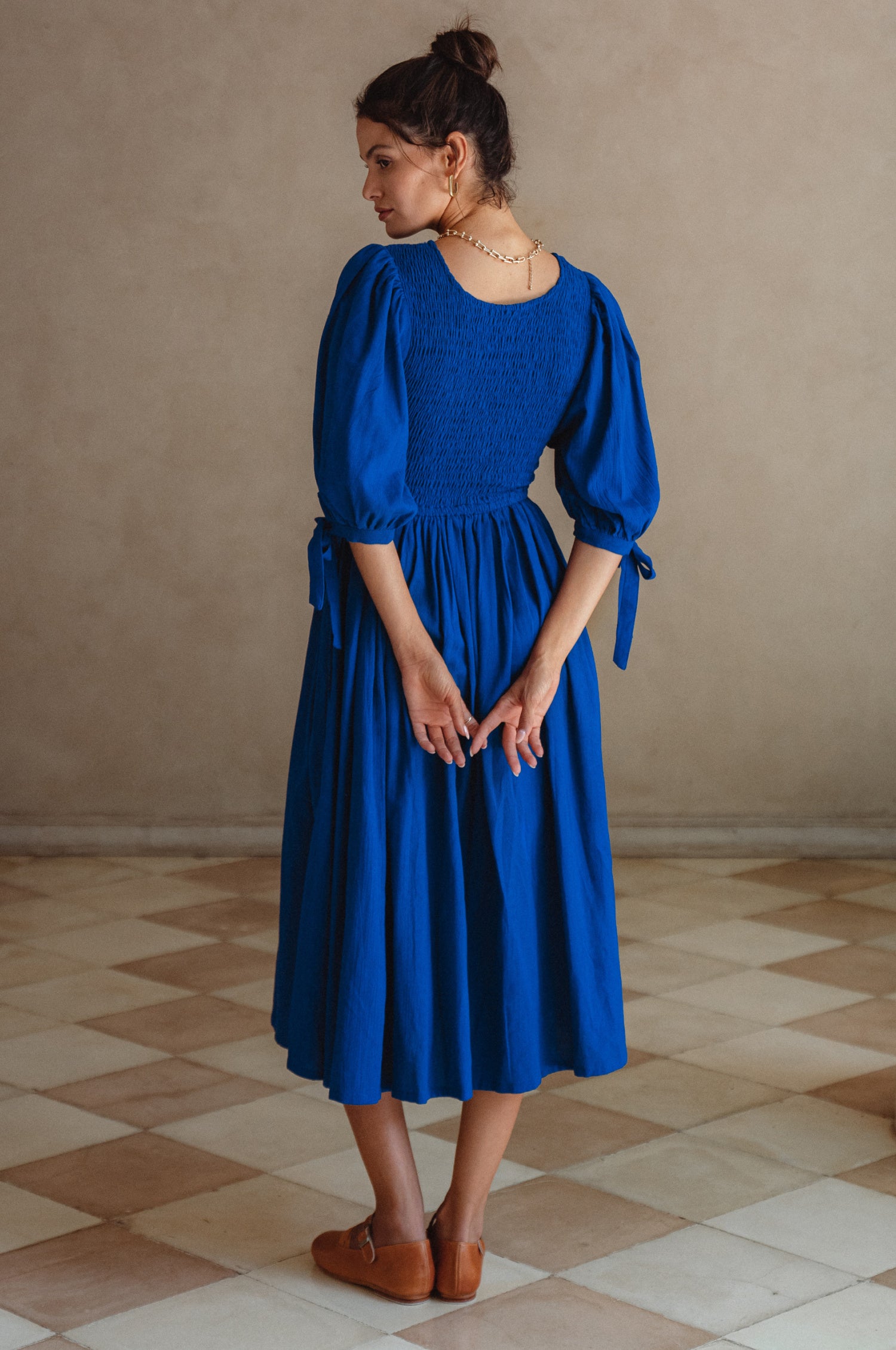 Freya Smocked Linen Midi Dress featuring a smocked bodice and tie-up puffy sleeves in a light crinkle linen fabric.