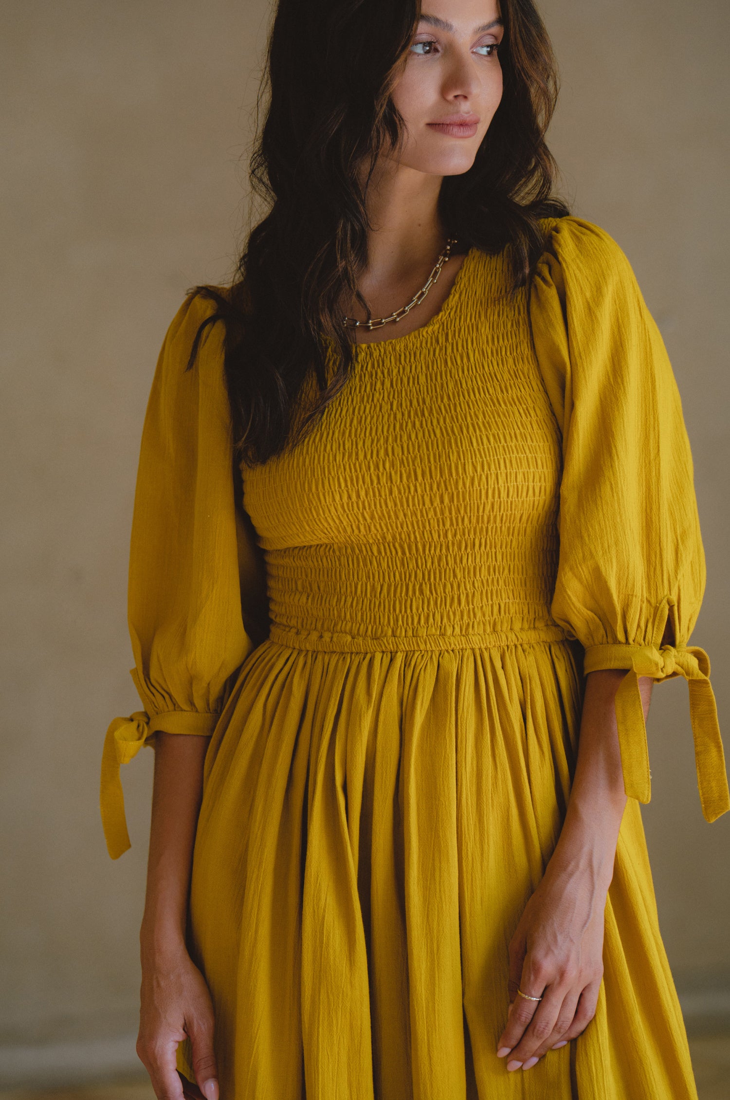 Freya Smocked Linen Midi Dress featuring a smocked bodice and tie-up puffy sleeves in a light crinkle linen fabric.