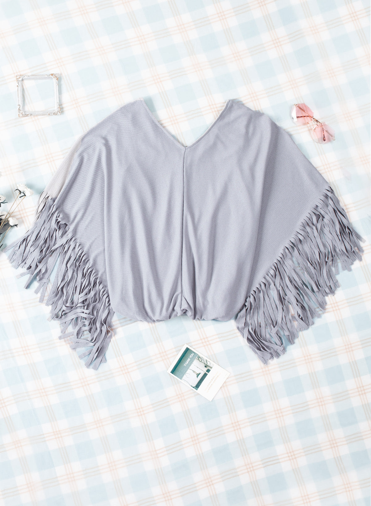 Fringe Trim Center Seam Dolman Sleeve Top displayed outdoors in a flat lay style, showcasing its chic design and fringe detailing.